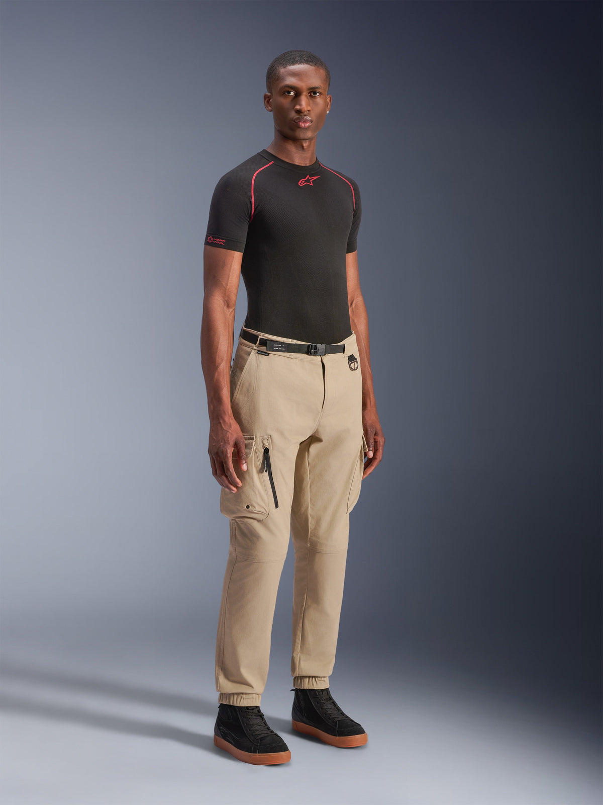 Alpinestars Flex-AST Cargo Pants - Short, lys beige urbane motorcykelbukser, båret af en model med sort basislag og sneakers, med en regular tapered pasform, elastiske sømme og cargo-design med flere lommer