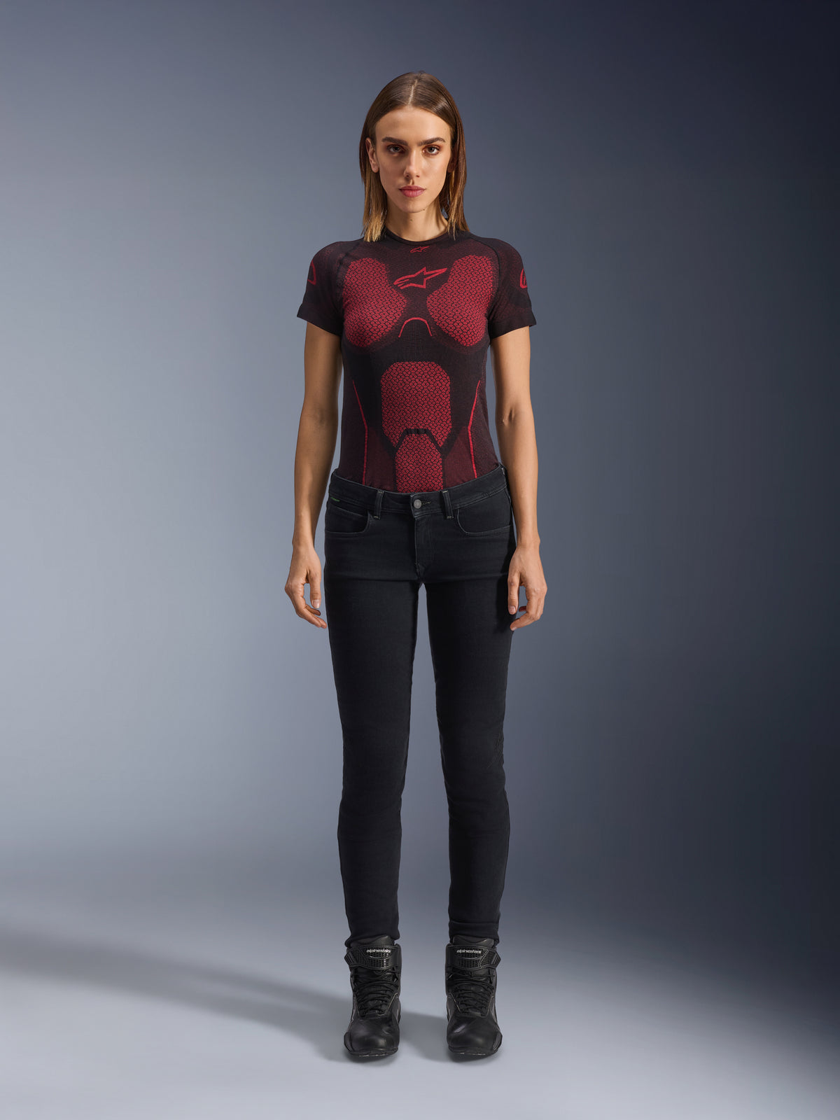 Alpinestars Daisy V3 kører-jeans til damer, Rinse Black, slim-fit motorcykelbukser, vist på en model med en rød og sort mønstret teknisk t-shirt og sorte motorcykelstøvler, casual urbant køreudstyr med en feminin silhuet og design med høj talje.