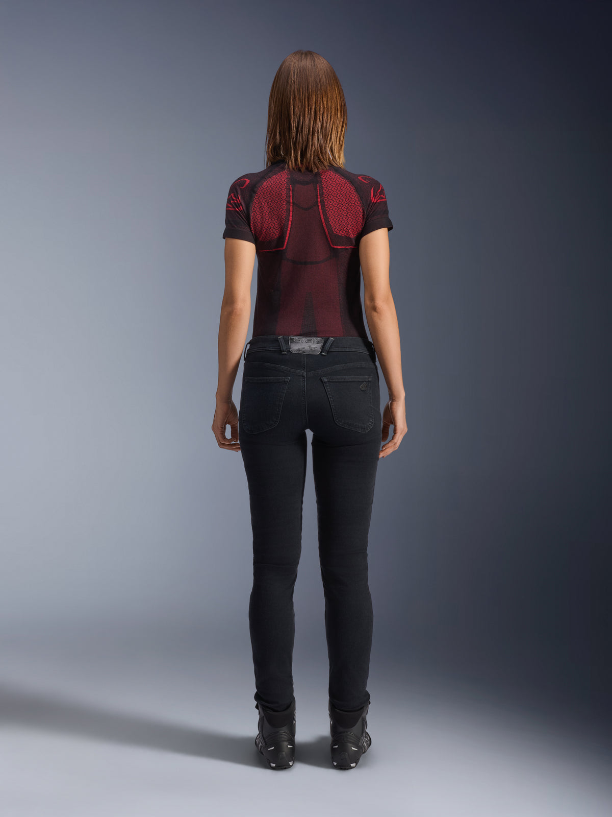 Alpinestars Daisy V3 motorcykeljeans til damer, Rinse Black, slim fit bukser set bagfra, design med høj talje og baglommer, stylet med rød og sort mønstret teknisk trøje og sorte støvler, urbant mc-udstyr til kvinder