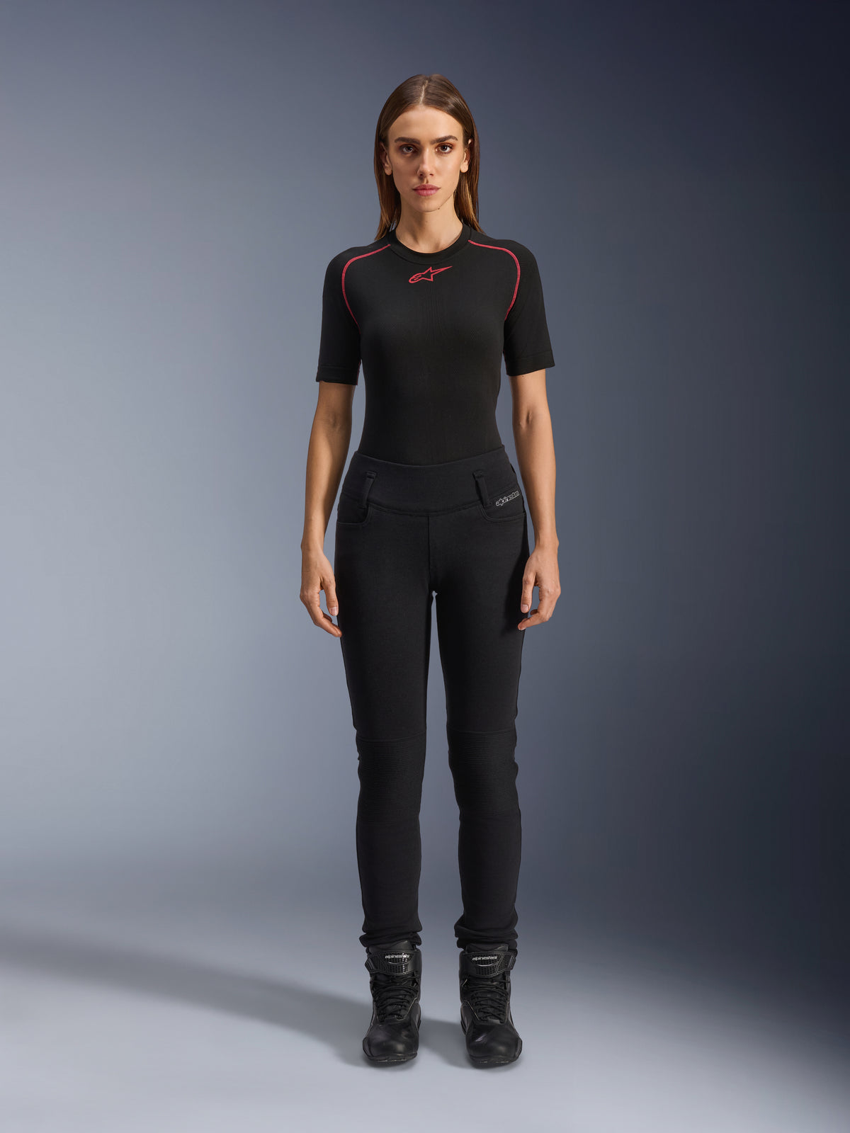 Alpinestars Womens Banshee Leggings, sorte motorcykel-leggings, kropsnær anatomisk pasform, båret af en kvindelig model med et sort basislag og motorcykelstøvler, med ribbede knæpaneler og højtaljet konstruktion til urban kørsel.