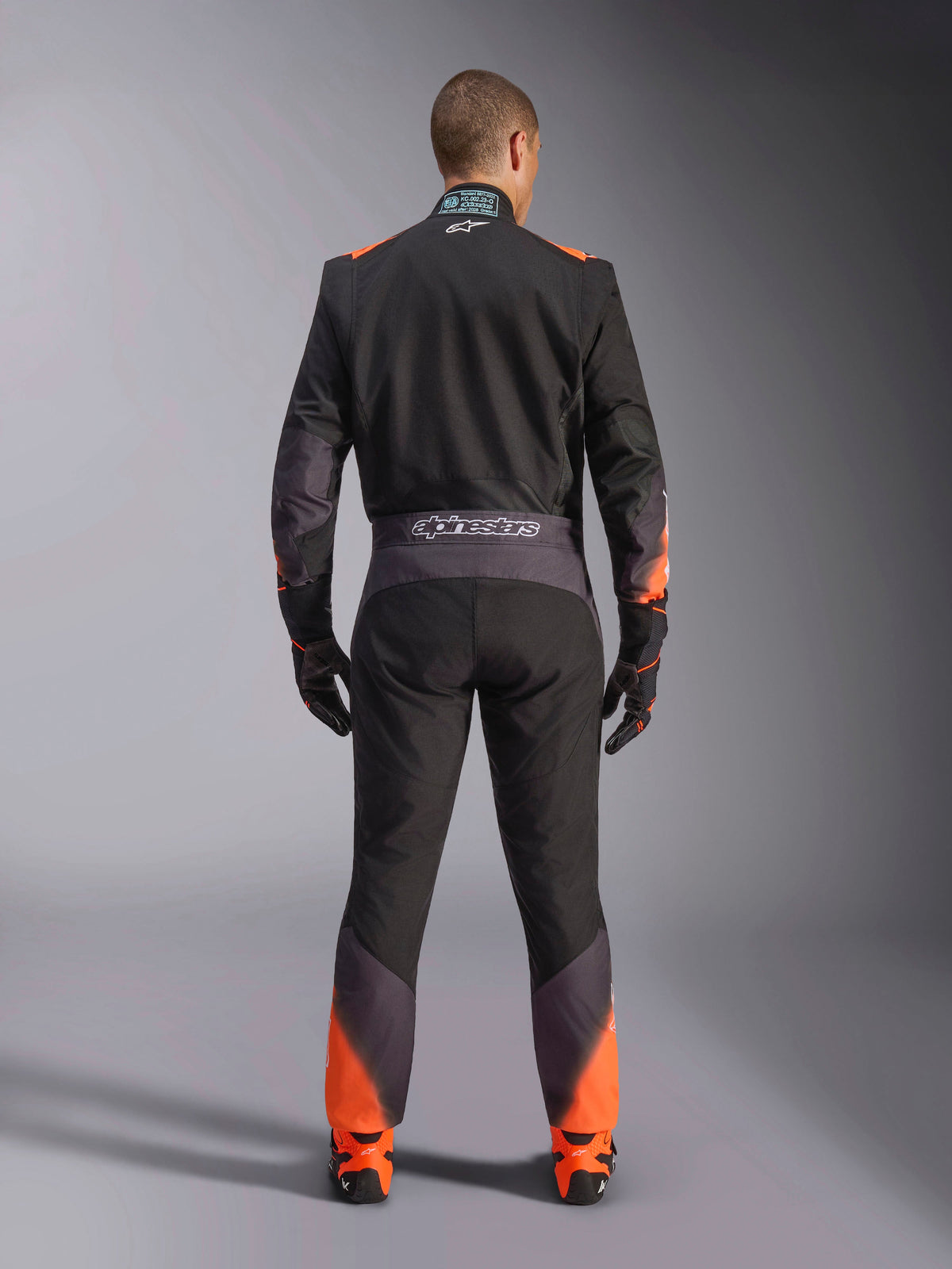 Alpinestars KMX-5 V3 Køredragt til herrer, etdelt og FIA-certificeret, sort og orange fluo, set bagfra med branding.