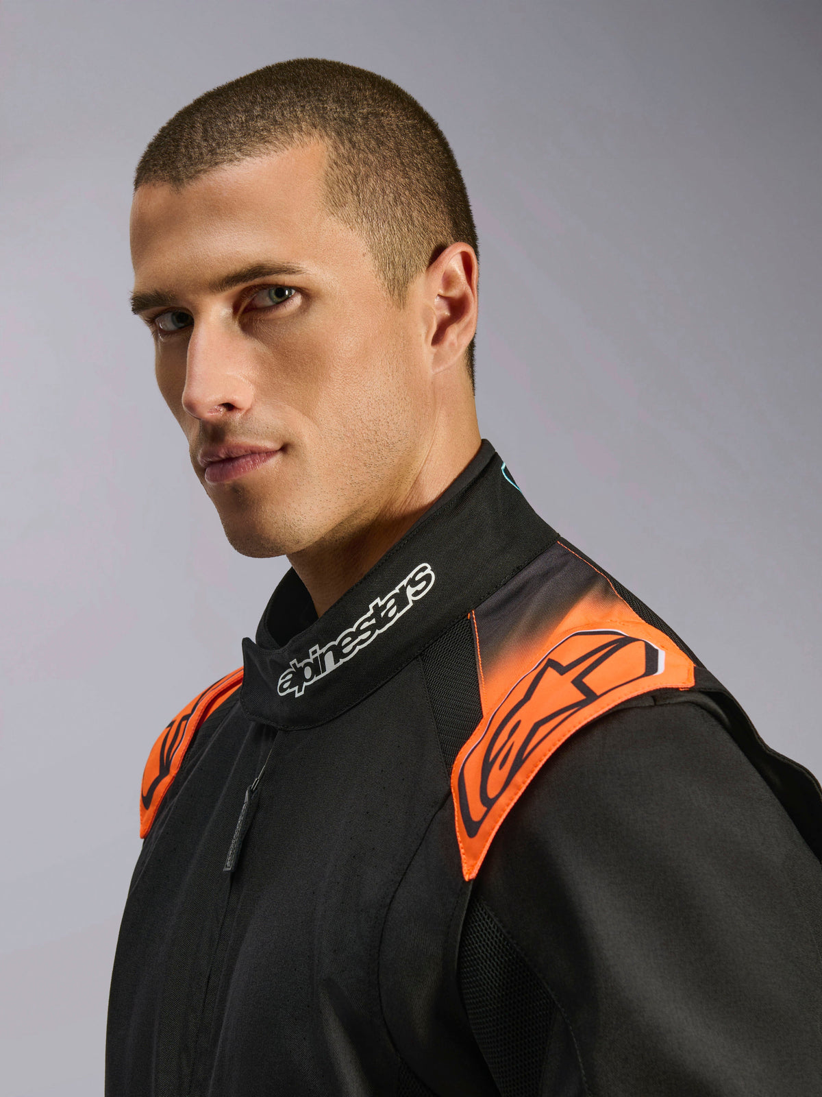 Alpinestars KMX-5 V3 køredragt, kartingdragt, sort og orange fluo, FIA-certificeret, modeldetalje af krave og skuldre.