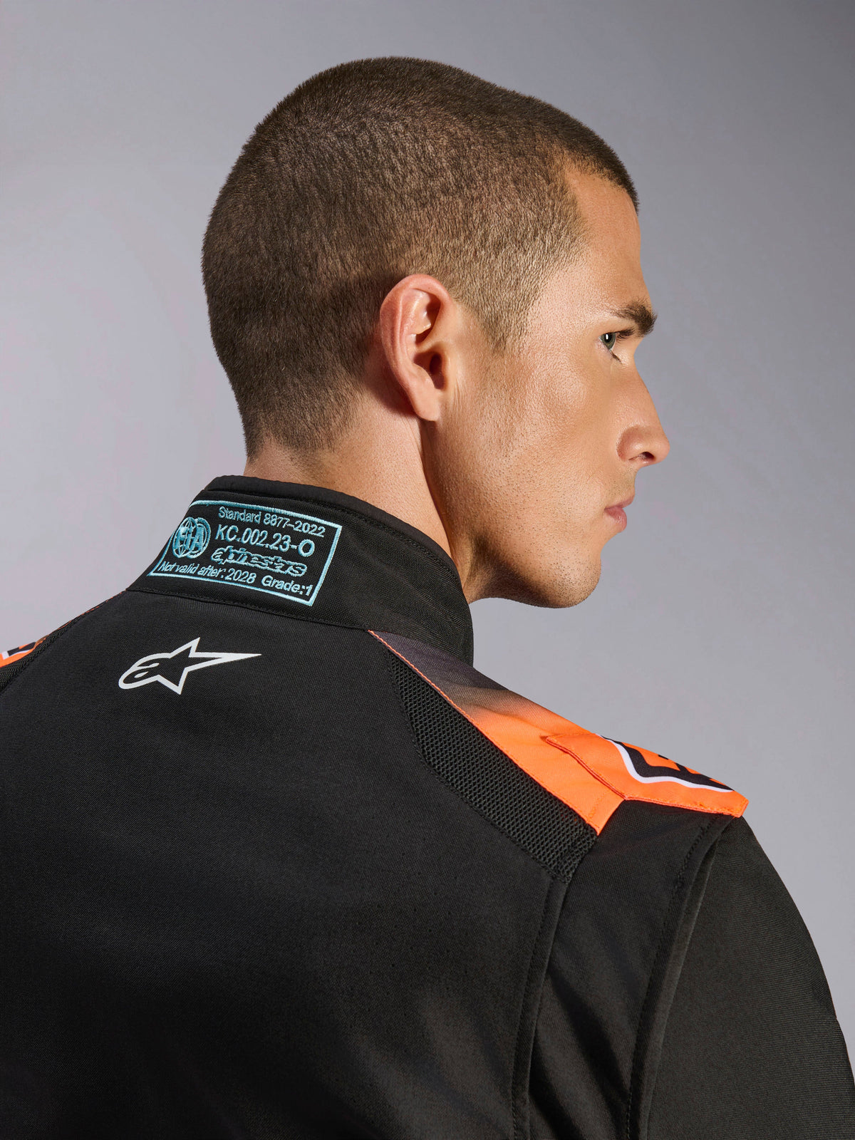 Alpinestars KMX-5 V3 køredragt til karting, sort og orange fluo, FIA 8877-2022 Grade 1-certificeret med tekniske meshpaneler.