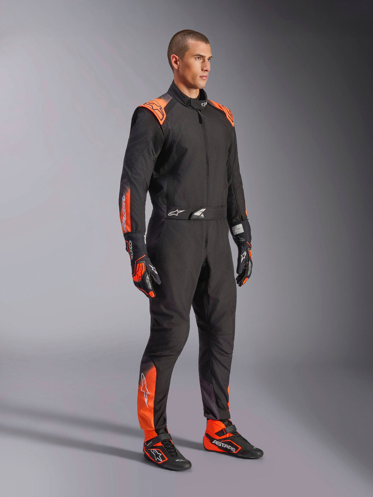 Alpinestars KMX-5 V3 køredragt, herrekartingdragt i sort og orange fluo, FIA Klasse 1 tekstilheldragt båret af en model.