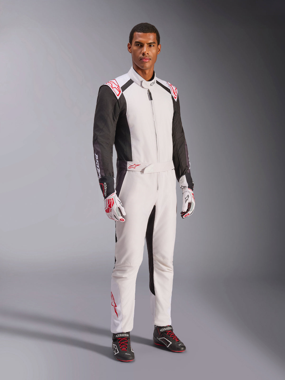 Alpinestars KMX-5 V3-dragt, hvid, sort og lys rød, heldragt til karting båret med matchende hvide og røde handsker og sorte racersko, med sorte ærmer og markante røde detaljer, professionelt motorsportsudstyr til konkurrencepræget karting
