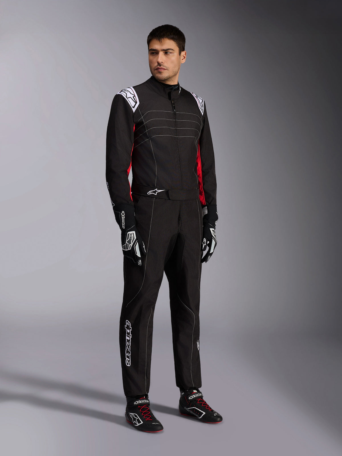 Alpinestars KMX-9 V3 Suit, Black Red White karting suit worn by a model, featuring white epaulettes and logos, red side accents, paired with matching racing gloves and shoes, professional motorsport apparel