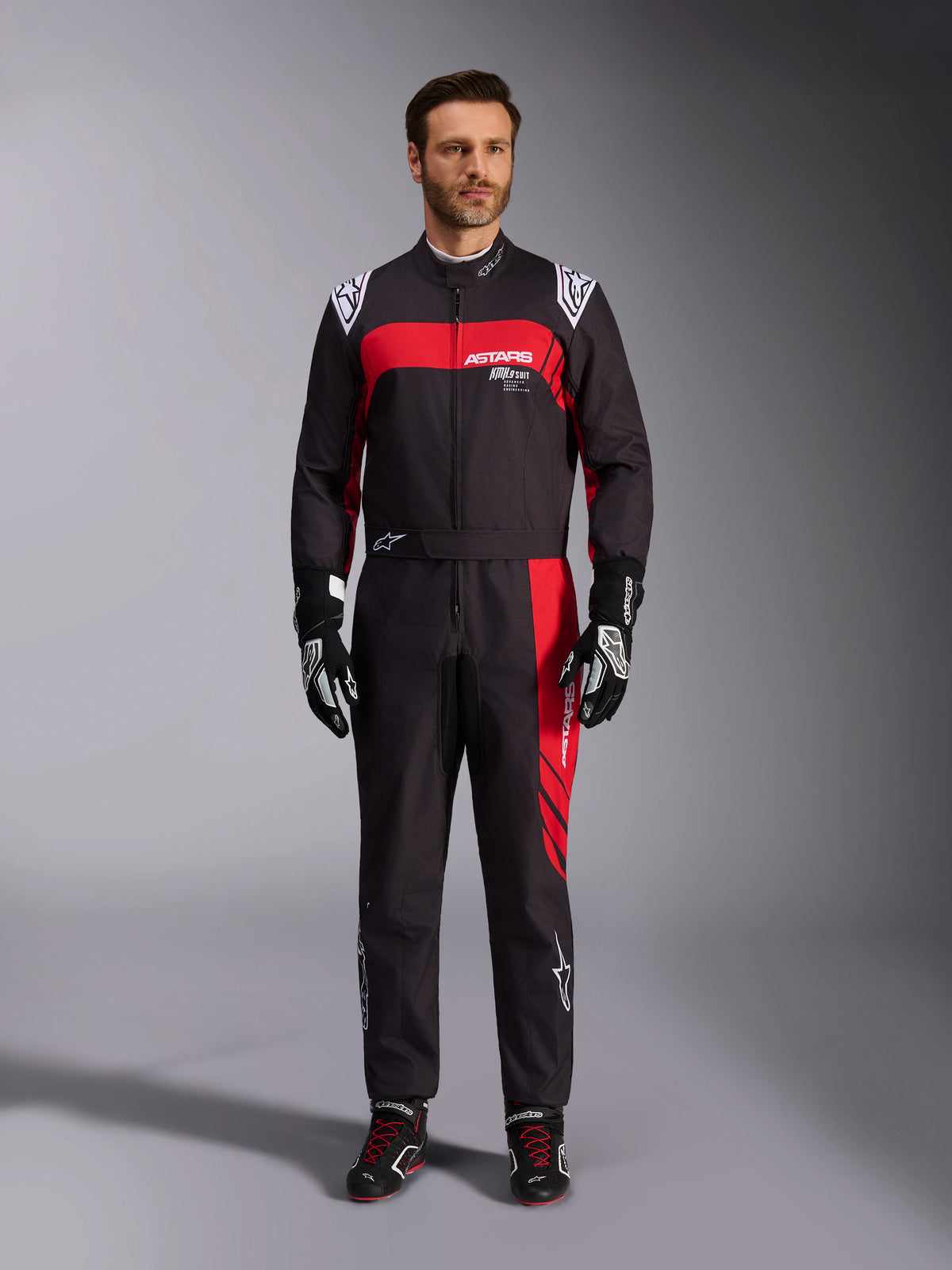 Alpinestars KMX-9 V3 Graphic 3 køredragt, kartingdragt, sort og rød, helkropsvisning forfra båret af en model, markante røde grafikpaneler og hvid branding, sorte racerhandsker og sko, professionelt motorsportstøj