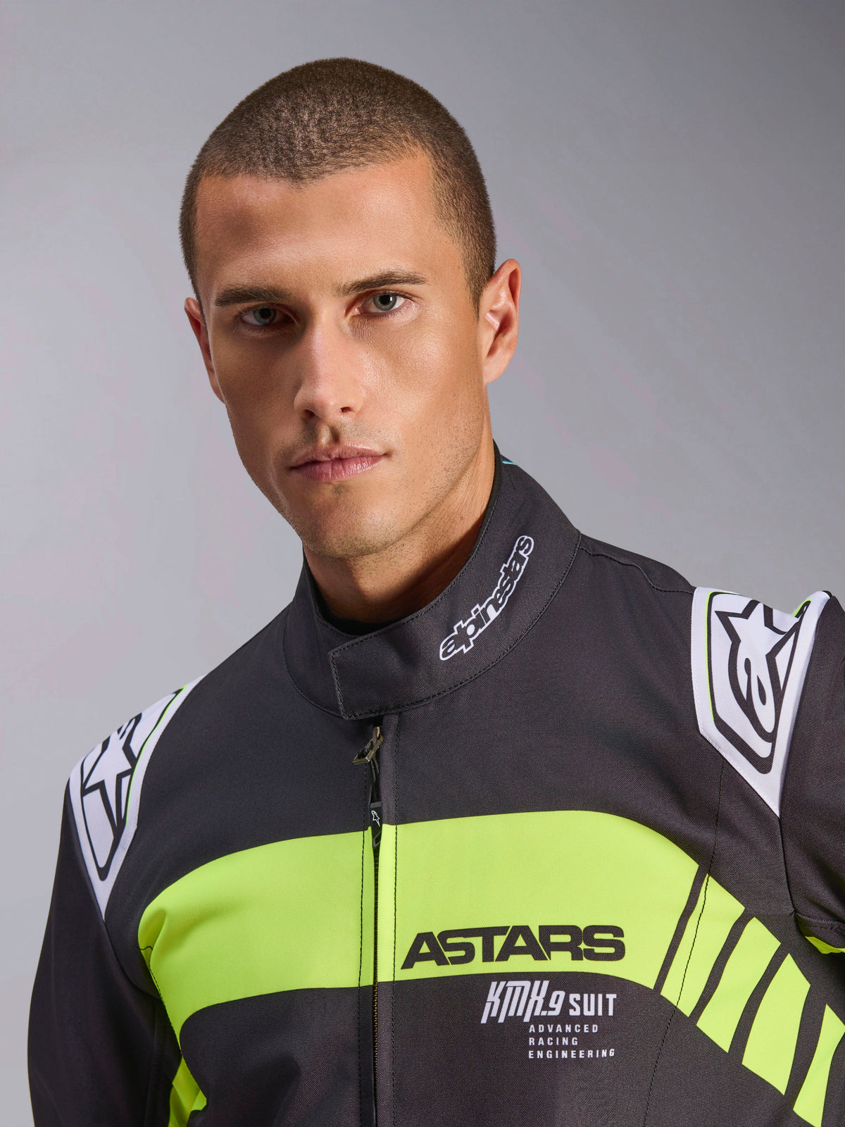 Alpinestars KMX-9 V3 Graphic 3 køredragt, kartingdragt, sort og fluoriserende gul, nærbillede med en fluoriserende gul bryststribe med ASTARS- og KMX.9 SUIT-branding, Alpinestars-logoer på skuldrene og kraven, professionelt racerudstyr