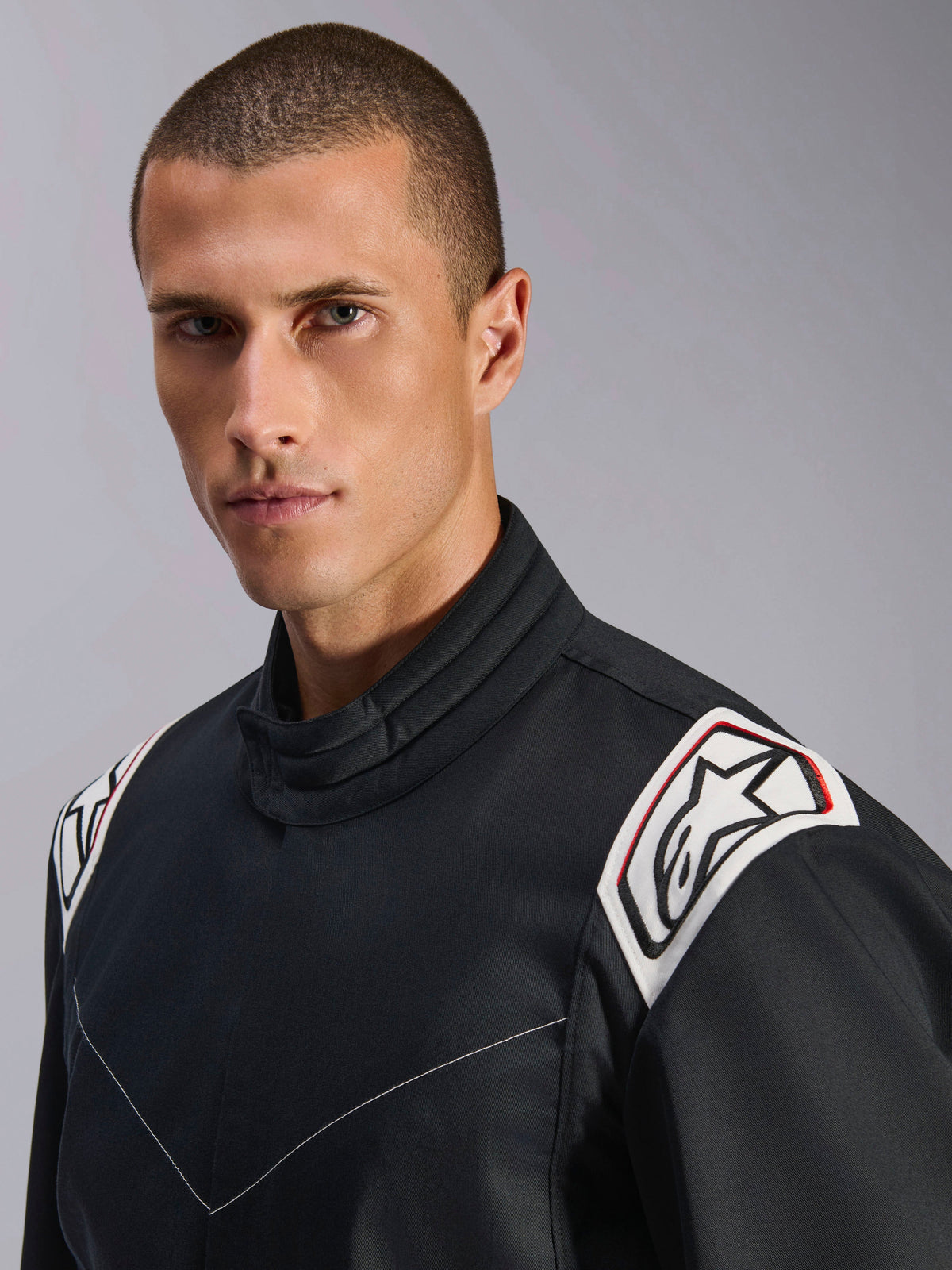 Alpinestars Kart Indoor V2 Suit, sort, nærbillede af skuldre og krave, hvide skulder-epoletter med sort Astars-logo, ergonomisk kravedesign, slidstærk poly-bomuld twill-konstruktion til indendørs karting