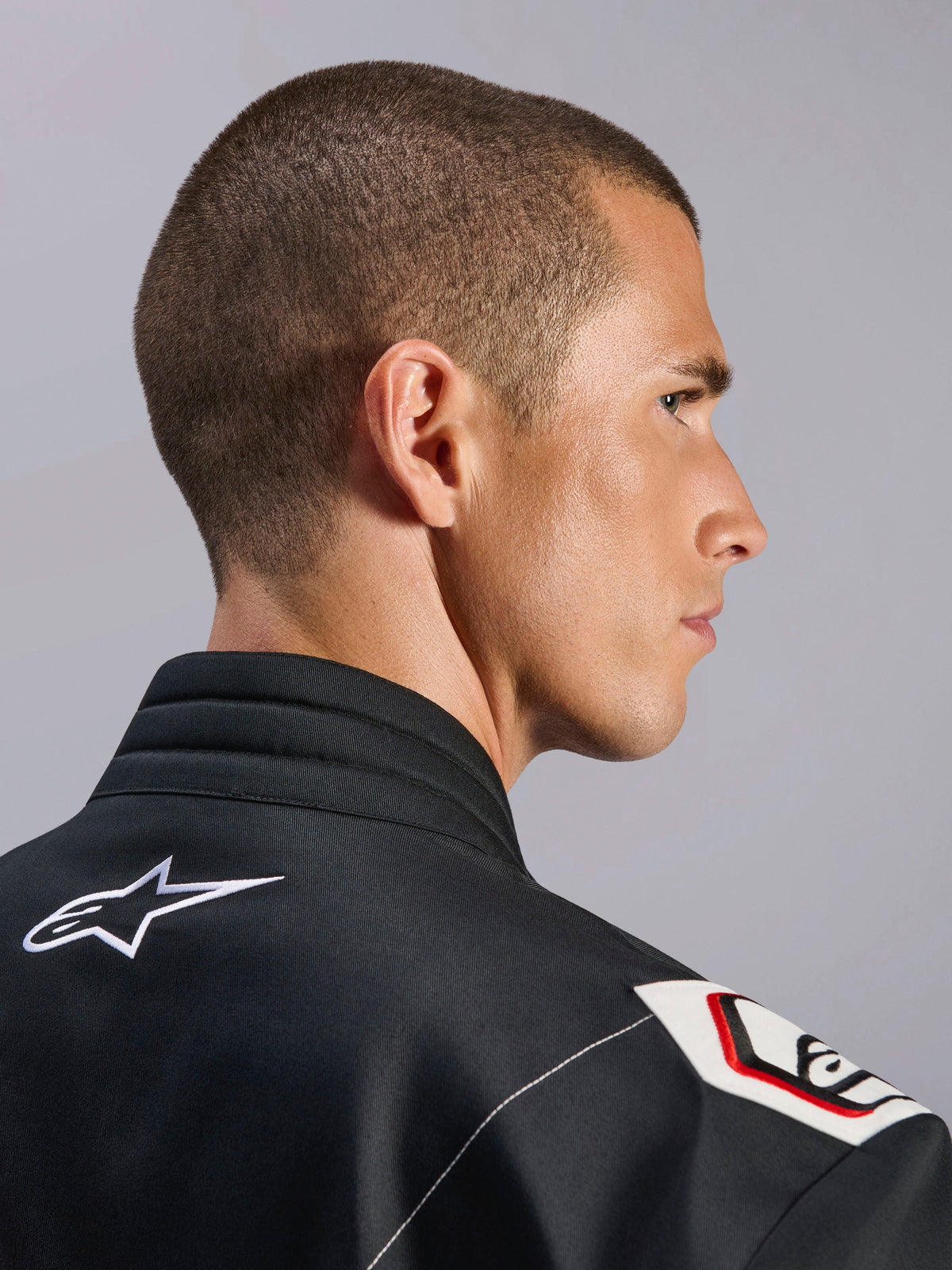 Alpinestars Kart Indoor V2 Suit, sort, nærbillede af den ergonomiske krave og Formel 1-afledte skulderdesign, med hvidt Alpinestars-logo og racing-inspirerede detaljer på slidstærkt twill-stof