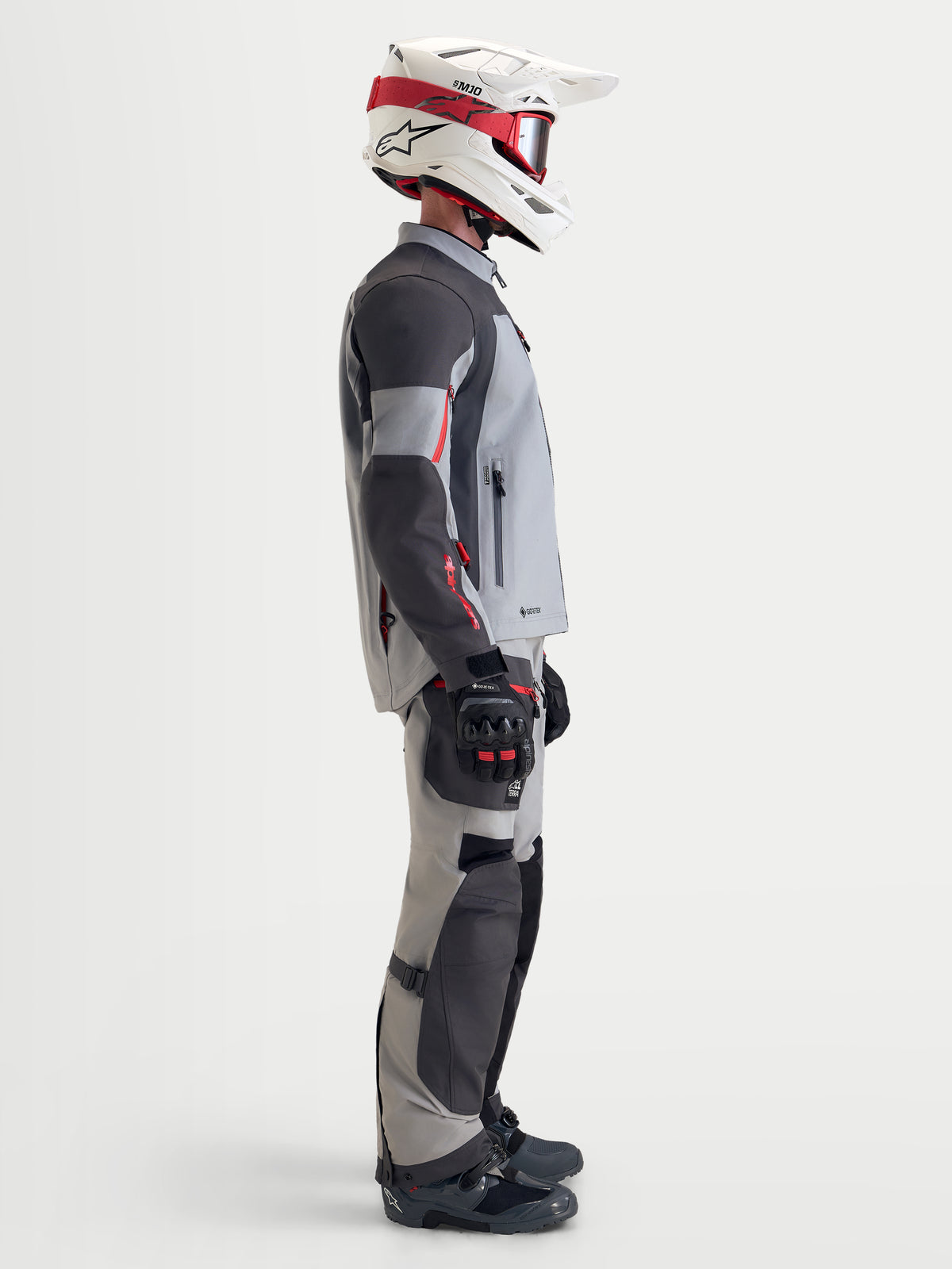Alpinestars Arenis Gore-Tex udstyrssæt, herre adventure-motorcykeljakke og -bukser i grå og sort, sideprofil af model iført matchende udstyr og hjelm, vandtæt all-terrain køretøj