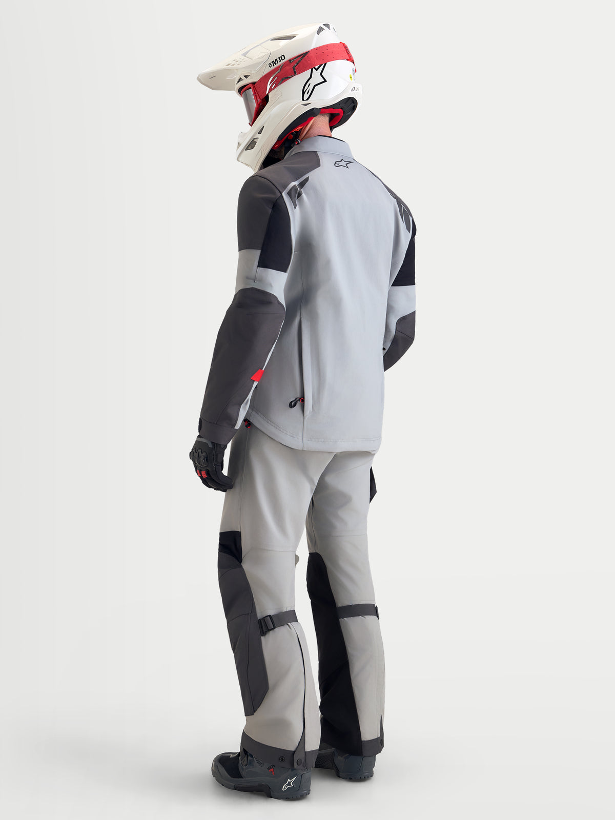 Alpinestars Arenis Gore-Tex udstyrssæt, herre adventure-motorcykeljakke og bukser i lysegrå og sort, set bagfra på en model iført matchende udstyr og hjelm, vandtæt tekstilkonstruktion