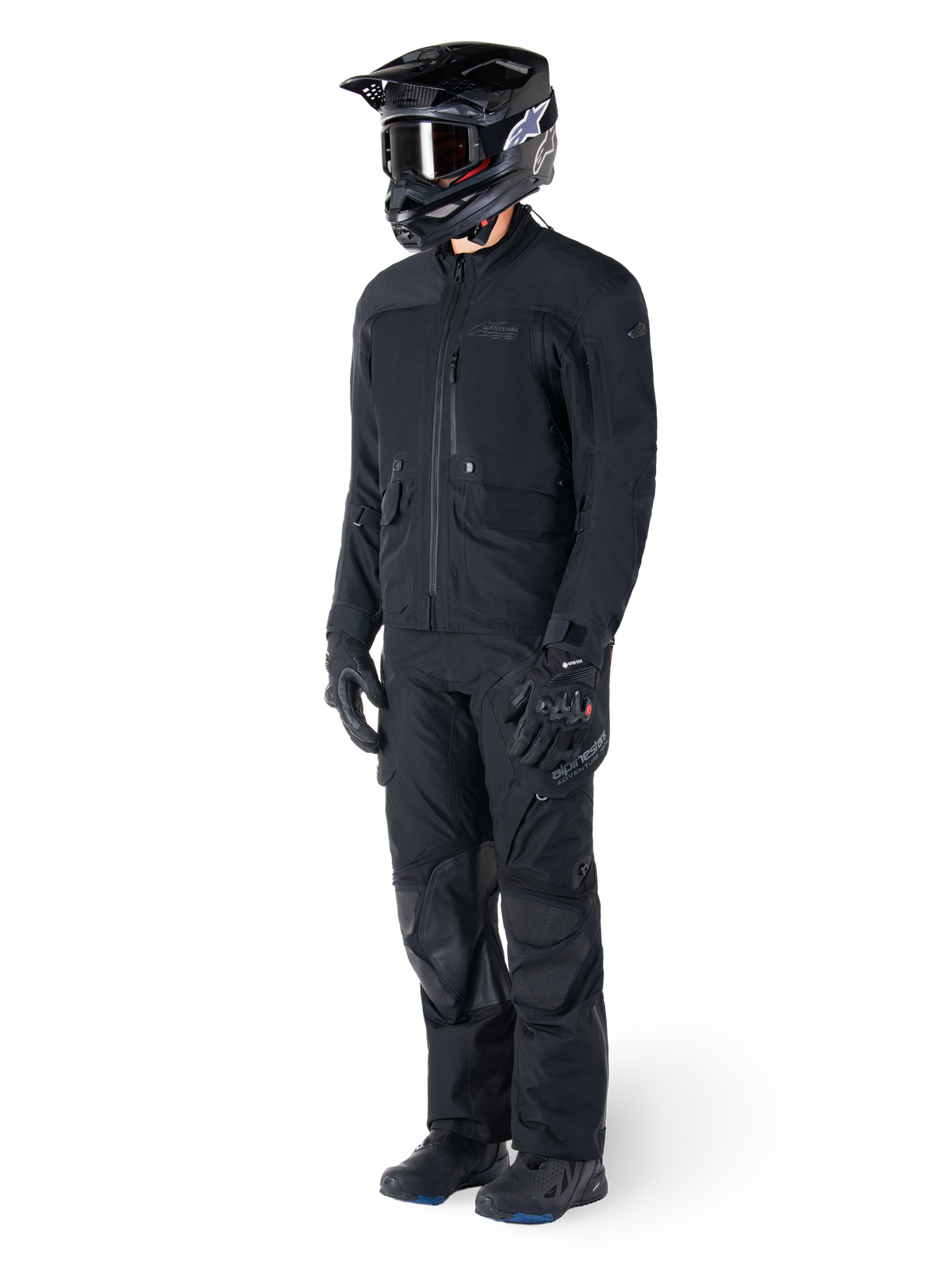 Motorcyklist iført Alpinestars St-7 Prime GORE-TEX-jakke i sort, koordineret adventure touring-outfit med matchende sorte bukser, sort hjelm med goggles og handsker, med et strømlinet og funktionelt design til ydeevne i al slags vejr.