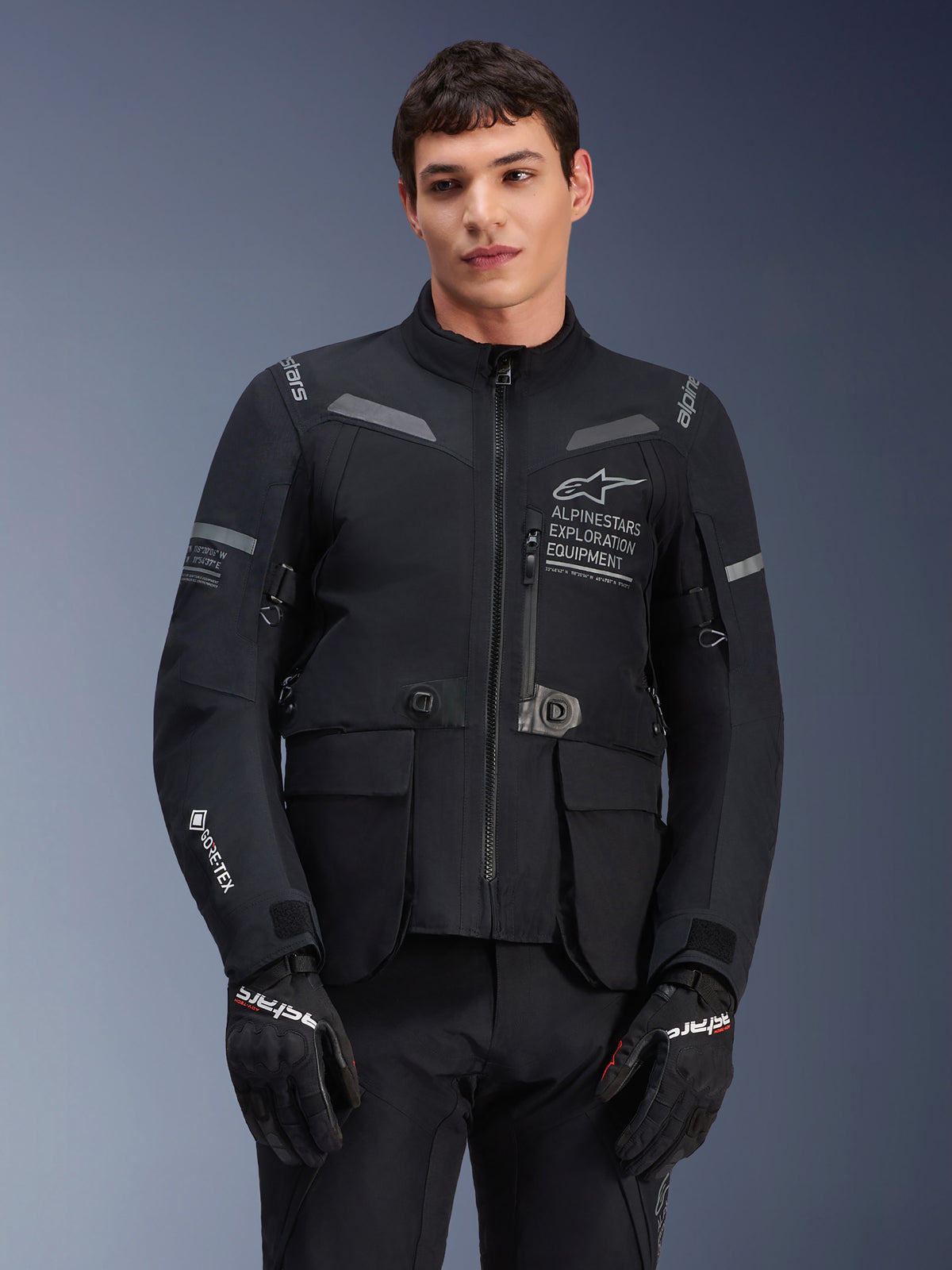 Alpinestars ST-7 2L GORE-TEX jakke, motorcykeljakke til touring, sort og mørkegrå, med Alpinestars Exploration Equipment-branding på brystet, store vandtætte cargolommer, GORE-TEX-logo på ærmet, robust adventure-klart design med reflekterende detaljer