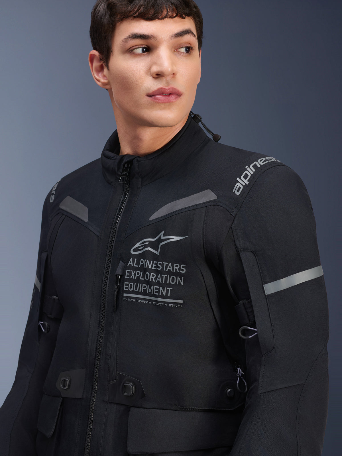 Alpinestars ST-7 2L GORE-TEX-jakke, motorcykeljakke, sort og mørkegrå, båret af en mandlig model, med Alpinestars Exploration Equipment-branding på brystet, reflekterende grå detaljer og adventure-klar tekstilkonstruktion