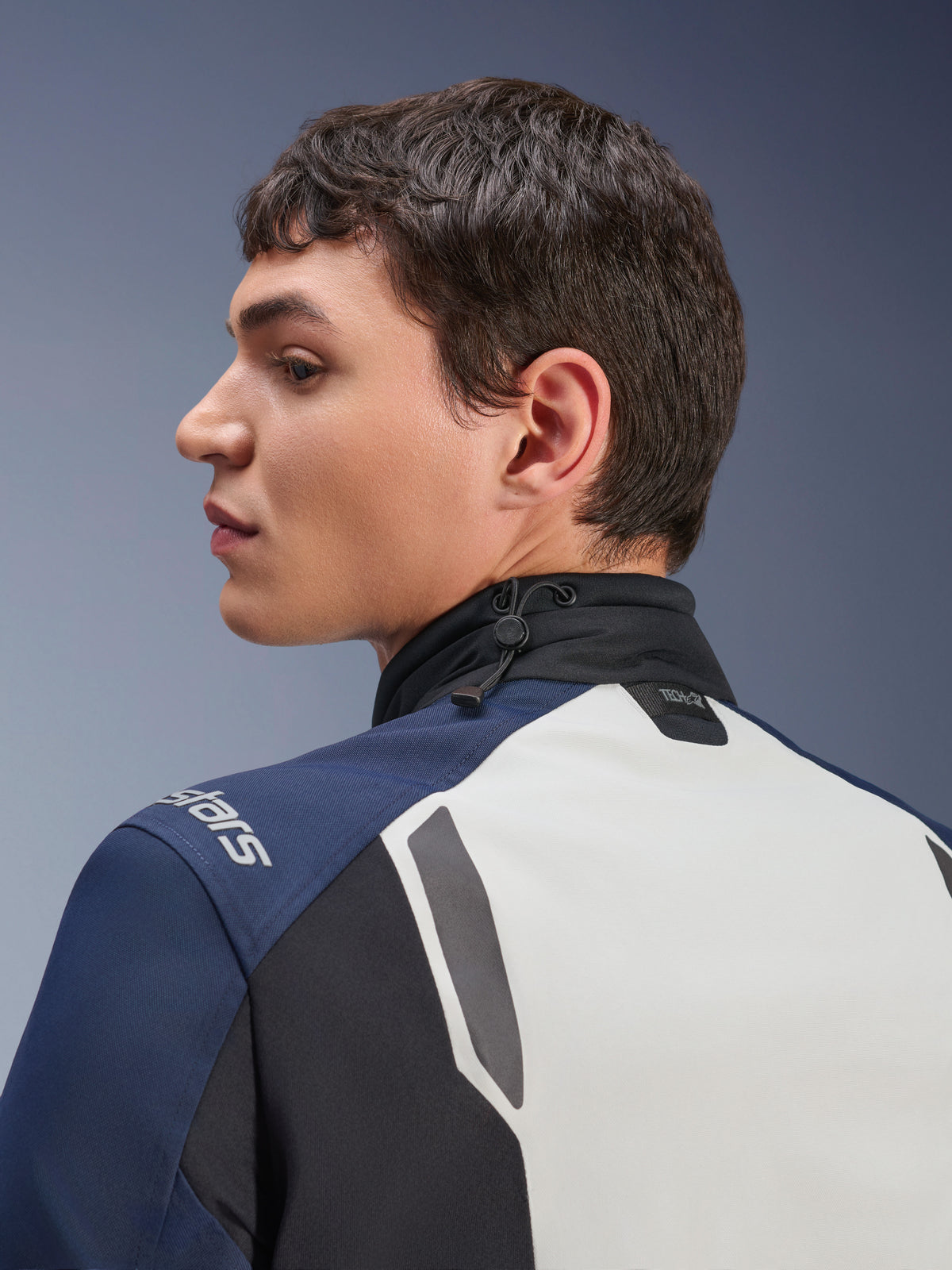 Alpinestars ST-7 2L GORE-TEX-jakke, nærbillede i profil af ryg- og halsområdet, Ice Gray, Dark Blue og sort, med justerbar krave med elastiksnøre og Tech-Air-branding, premium adventure touring-motorcykeljakke.