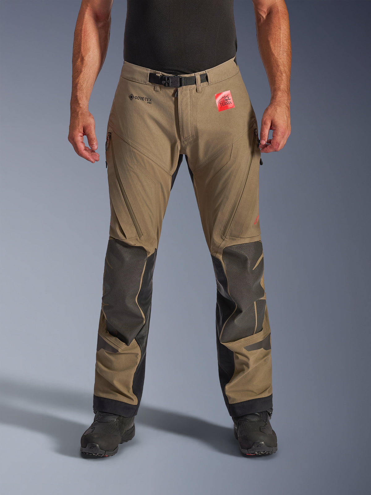 Alpinestars Nazca 3L GORE-TEX PRO Pants in Walnut Black, Men's Adventure Touring Pants, featuring brown textile with black Superfabric knee reinforcements, zippered thigh vents, and magnetic waist closure, front view on model with black boots, durable waterproof riding gear