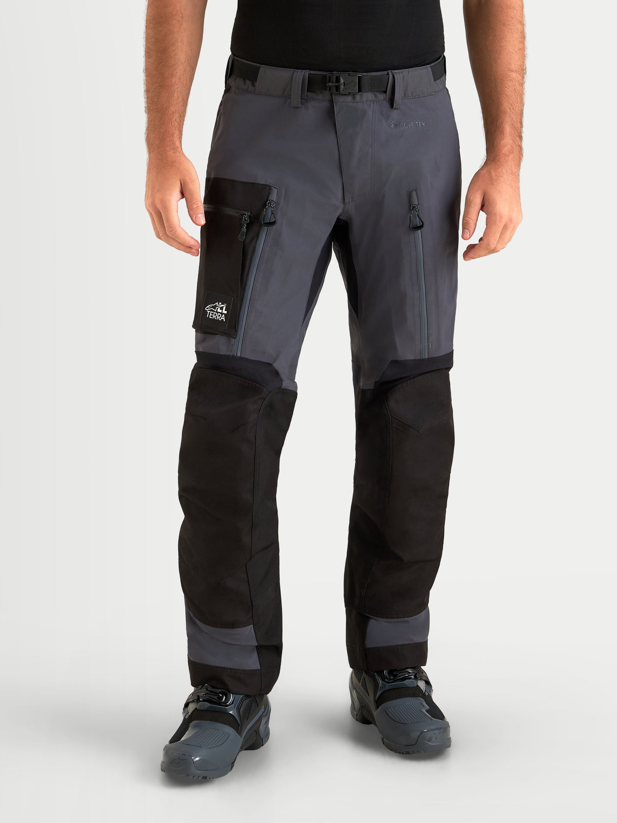 Alpinestars Arenis Gore-Tex Pants, men's adventure touring motorcycle pants in black and deep gray, front view on a model wearing waterproof textile riding apparel with cargo pockets and thigh vents.