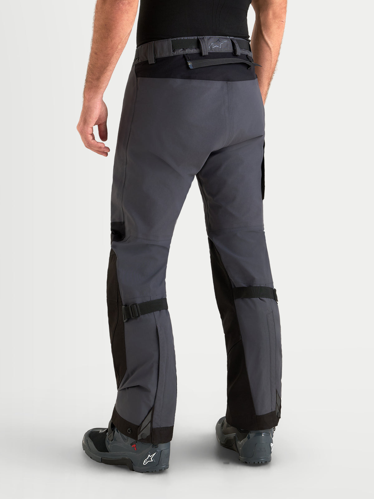 Alpinestars Arenis Gore-Tex bukser, herre adventure-motorcykelbukser i sort og mørkegrå, set bagfra på en model, der viser vandtæt tekstilkonstruktion og taljelukning