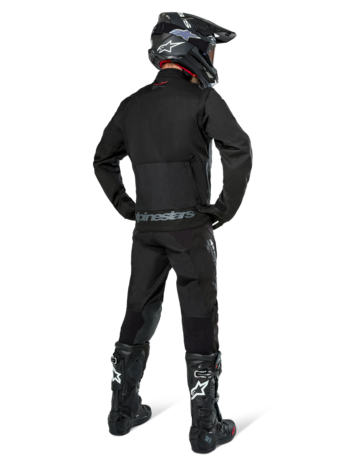 Alpinestars Pro-Dura jakke, sort off-road enduro-jakke, set bagfra båret med matchende bukser og sorte Tech 10-støvler, med fremtrædende Alpinestars-branding på den nederste del af ryggen, robust tekstilkonstruktion til aggressiv trail-kørsel