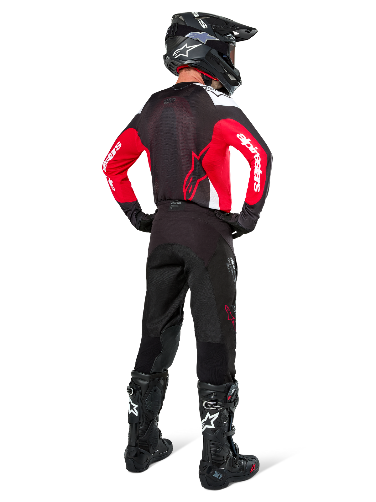 Alpinestars Pro-Dura bukser i Black Magnet White, motocrossrytter set bagfra, kombineret med rød og sort trøje og sorte støvler, koordineret off-road udstyrssæt til enduro-kørsel