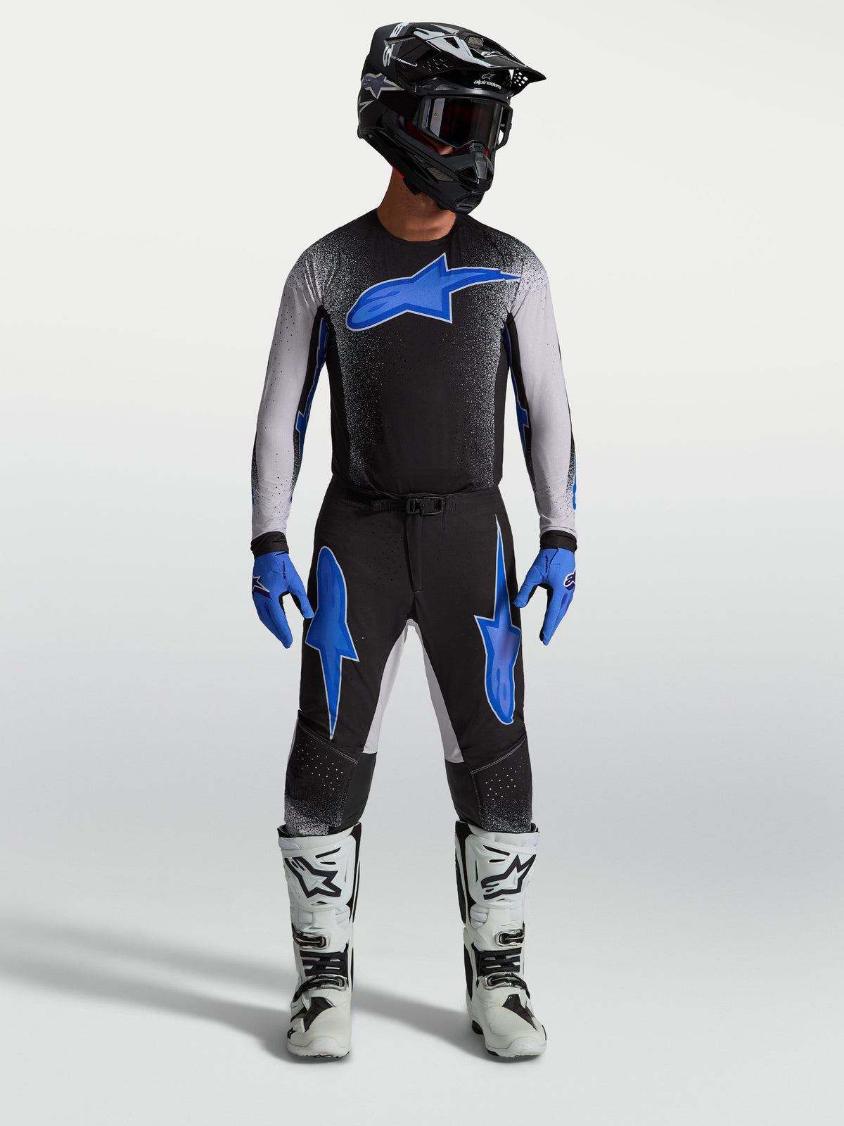 Alpinestars Supertech Hiten AFD bukser, sort og blå motocrossudstyr, på model med matchende trøje og hvide racerstøvler.