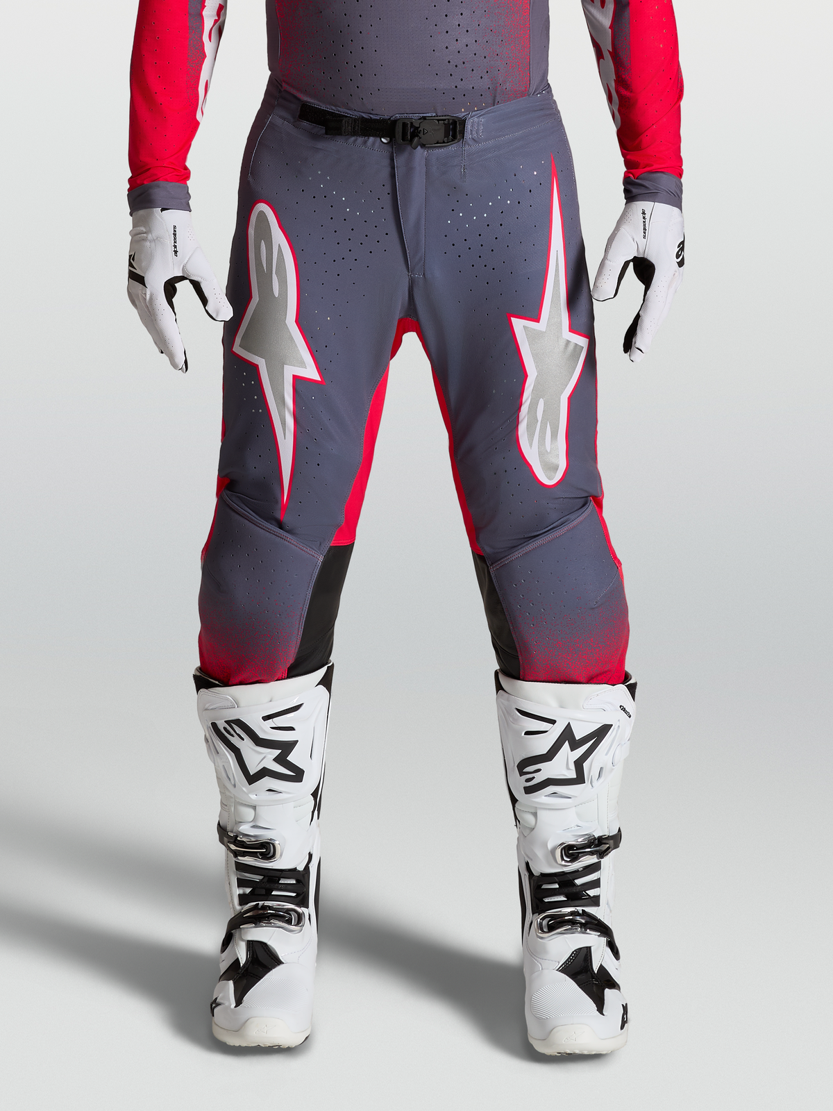 Alpinestars Supertech Hiten AFD bukser, motocrossbukser i grå og rød rød, på model med hvide støvler, perforeret stretch og stjernegrafik