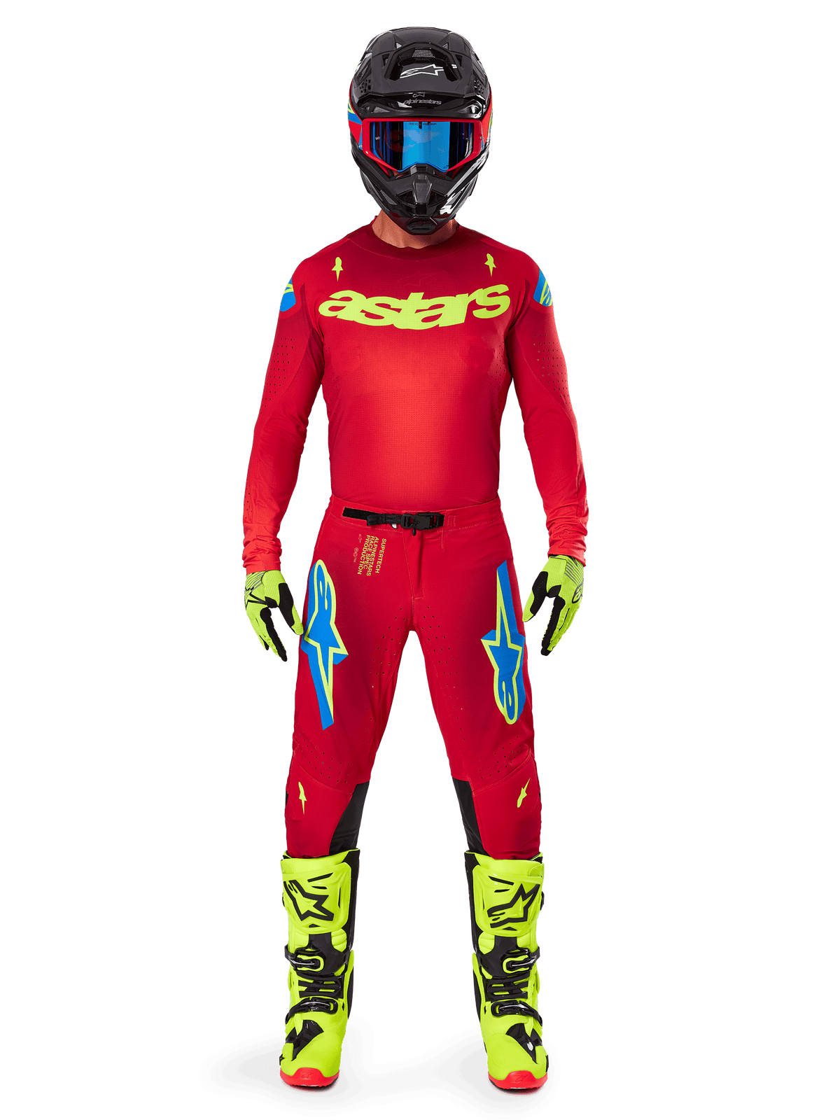 Motocrossrytter i komplet racerudstyr, rød trøje med neongult astars-logo, Alpinestars 2025 Supertech Maker-bukser i Bright Red og Yellow Fluo, blå logoer på lårene, neongule handsker og støvler, sort hjelm med blå goggles, professionelt koordineret motocross-outfit
