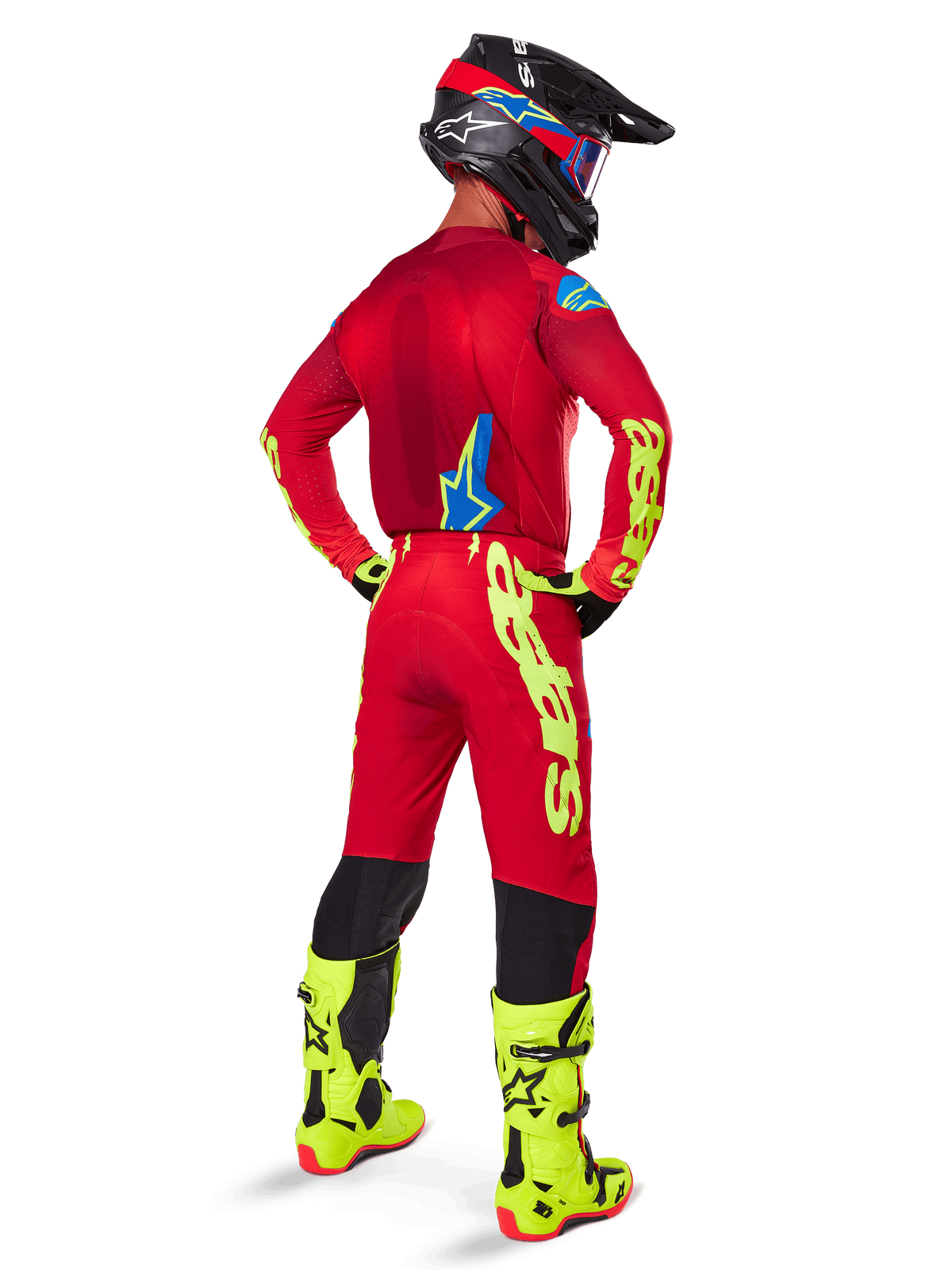 Alpinestars 2025 Supertech Maker bukser, motocross-bukser, lys rød og fluorescerende gul, set bagfra på en kører iført en matchende rød jersey, fluorescerende gule støvler og sort hjelm, med stort gult Alpinestars-logo på benet.