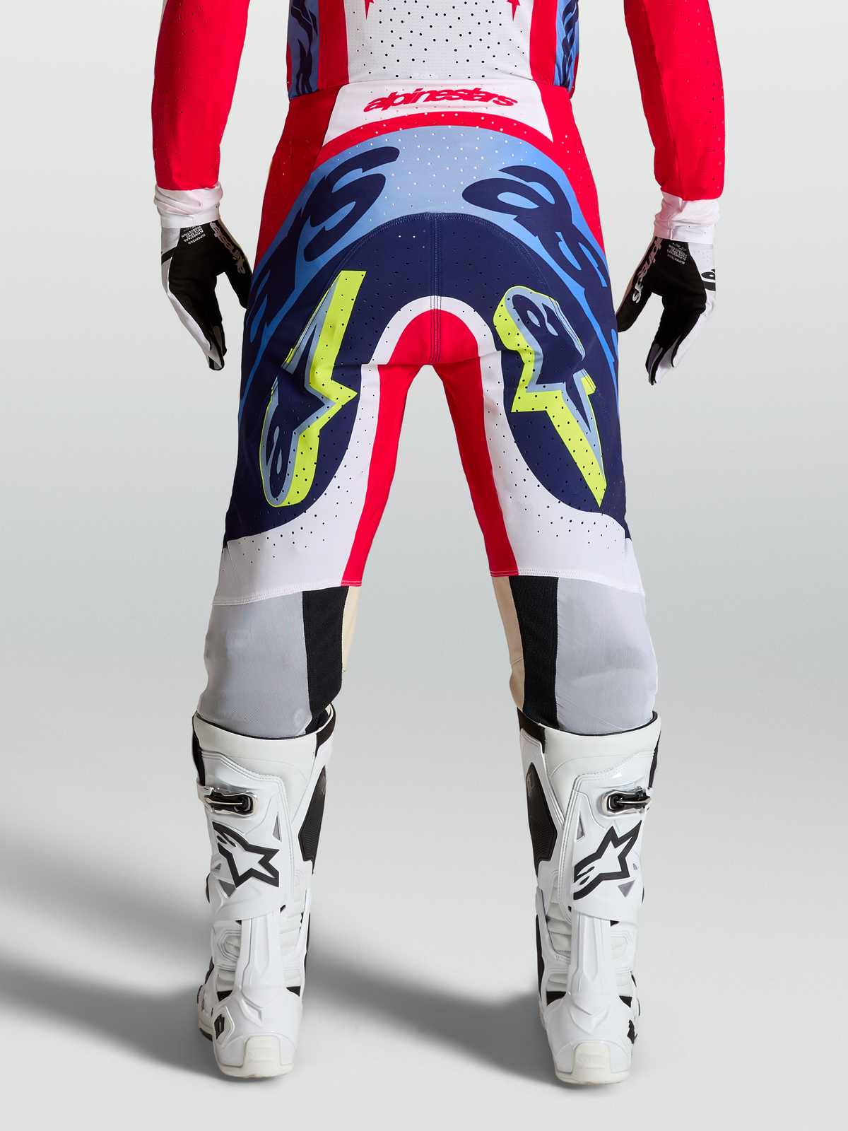 Rear view of Alpinestars Supertech Dyna Pants in fire red, white, and navy blue, showing durable motocross racing construction.