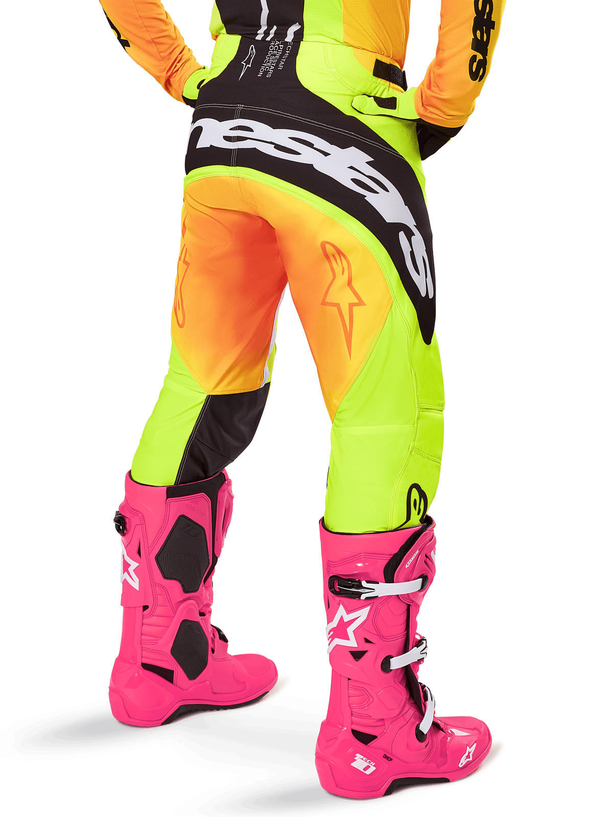 Bagfra af en motocrosskører iført Alpinestars 2025 Techstar Melt bukser, gul og orange farveovergang med sort og hvidt logo på bagdelen, kombineret med lyserøde motocross-støvler, performance off-road udstyr