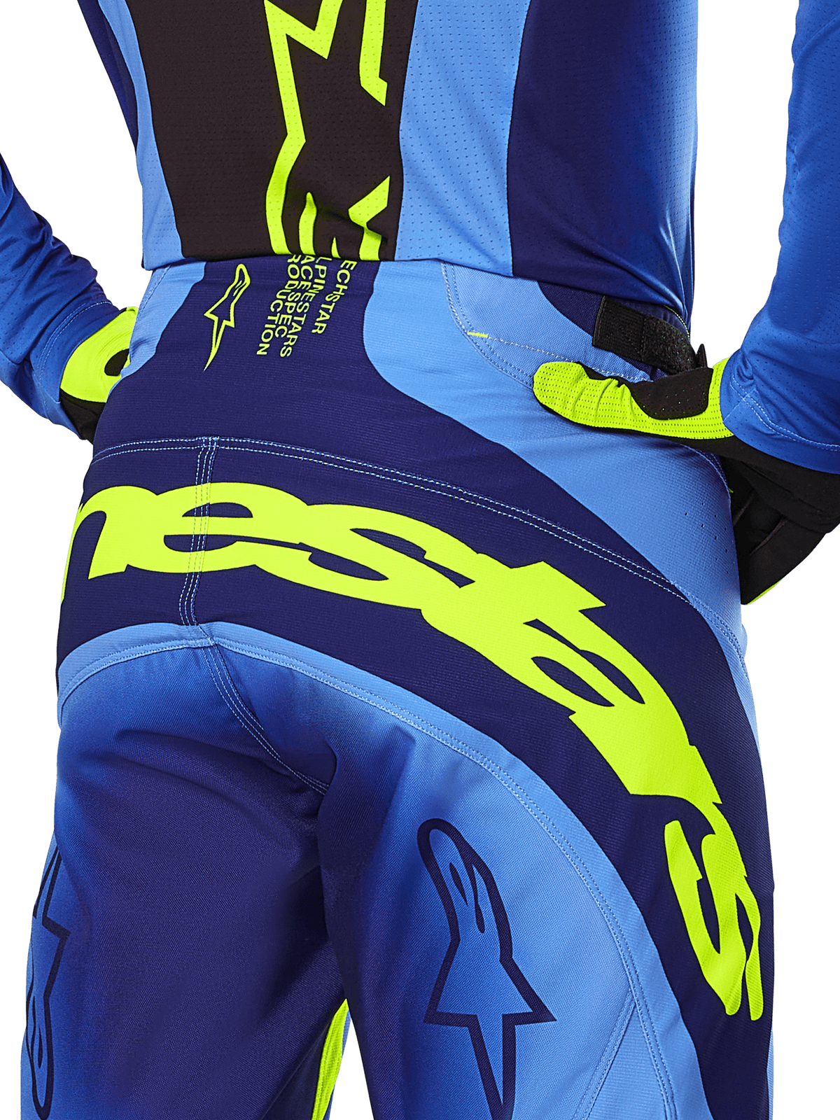 Alpinestars 2025 Techstar Melt bukser, motocrossbukser, gul fluo og blå, nærbillede bagfra med tydelig gul Alpinestars-branding over bagen, båret med matchende blå trøje og gul-fluo handsker, designet til performance off-road kørsel.