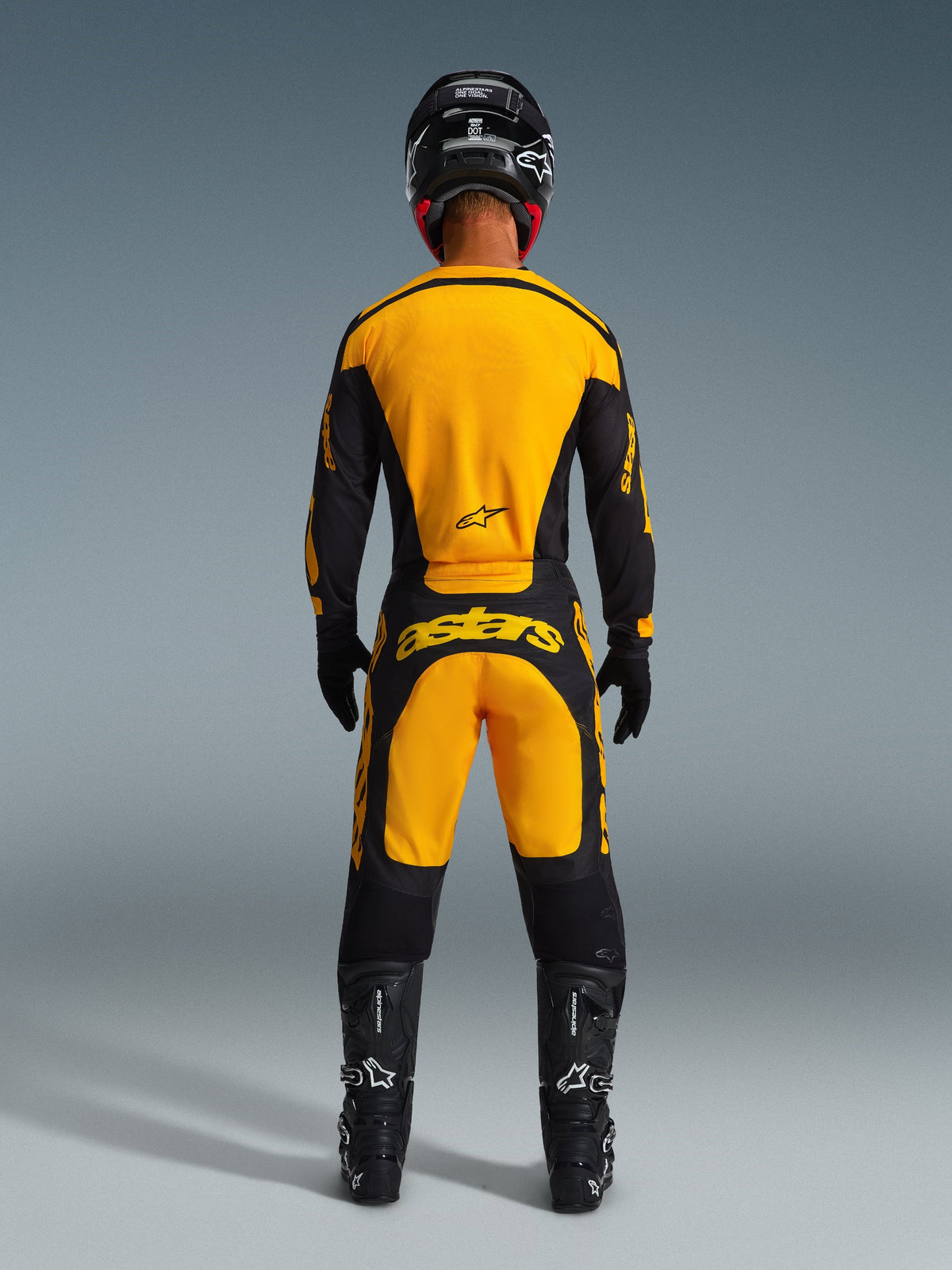 Motocrosskører set bagfra iført Alpinestars 2026 Racer Riway-bukser og matchende jersey i gul og sort, med markant gul branding på ryggen, kombineret med sort hjelm, sorte handsker og sorte motocross-støvler, komplet off-road racing-udstyrssæt