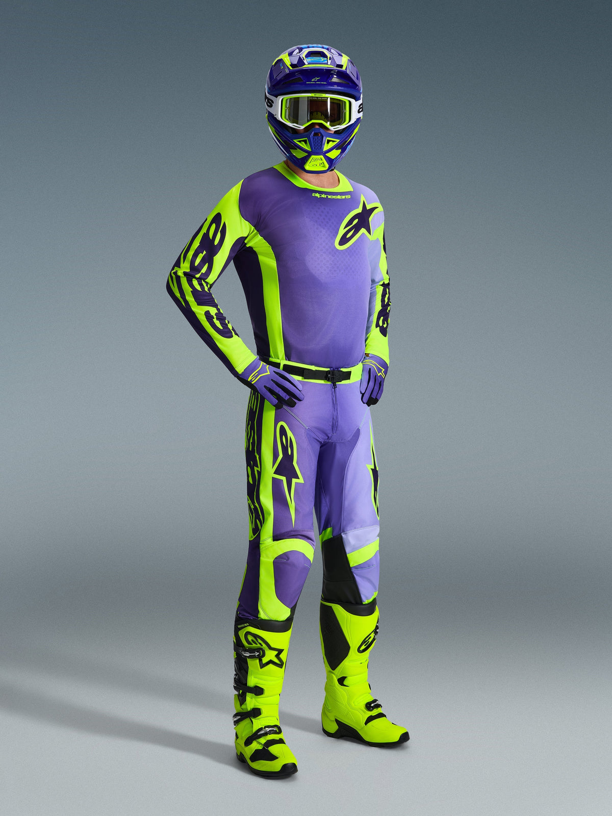 Motocross-kører iført Alpinestars 2026 Racer Portl-racerudstyr, lilla og neongul jersey og bukser, neongule støvler, lilla handsker og matchende hjelm, komplet koordineret sæt til off-road motocross.