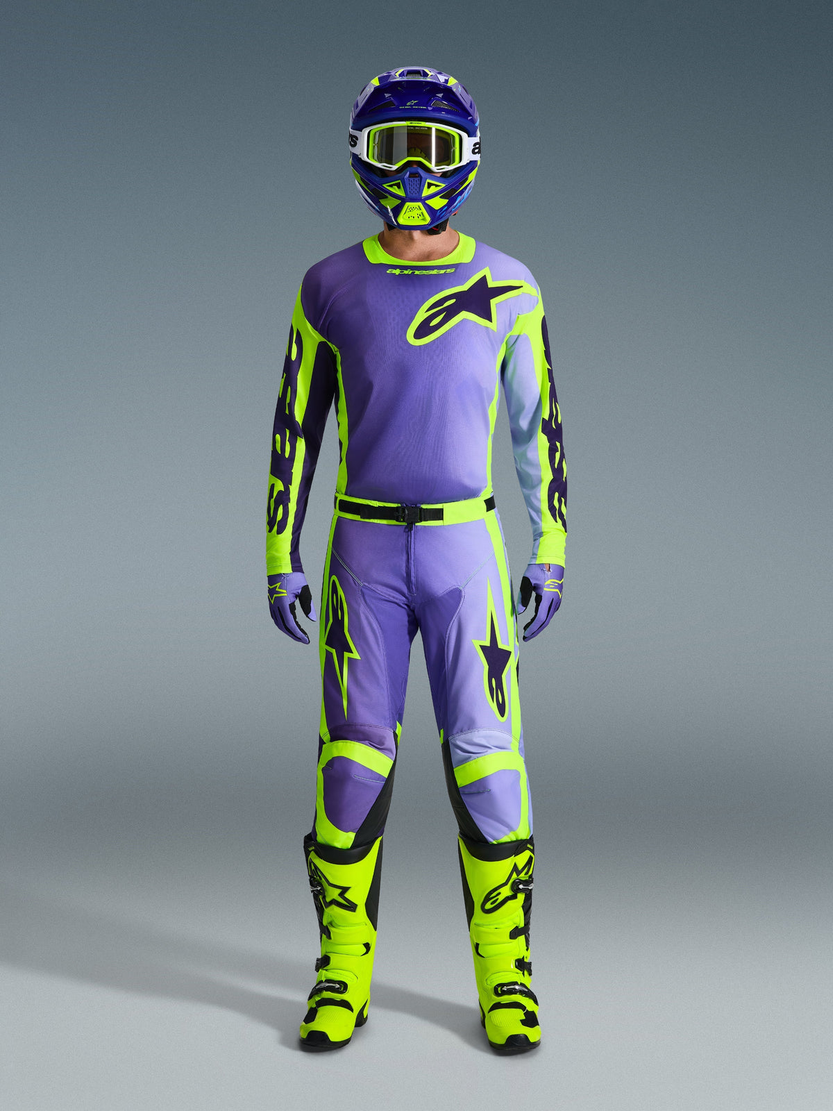 Alpinestars 2026 Racer Portl-bukser og matchende udstyrssæt, motocross-kører i Purple og Yellow Fluo, med koordineret trøje, hjelm, goggles og lysende gule støvler, designet til off-road performance.