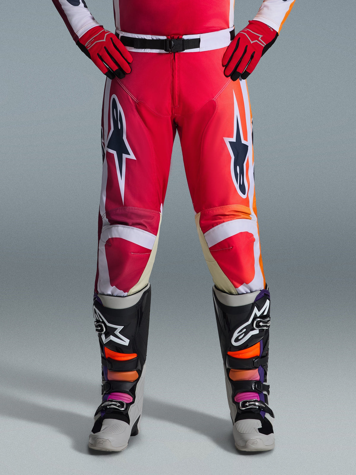 Alpinestars 2026 Racer Portl bukser, motocrossbukser, rød, lysegrå og mørkegrå, båret med matchende røde handsker og flerfarvede støvler, med markante Alpinestars-stjernelogoer på lårene og hvide detaljer, sporty design til off-road racing