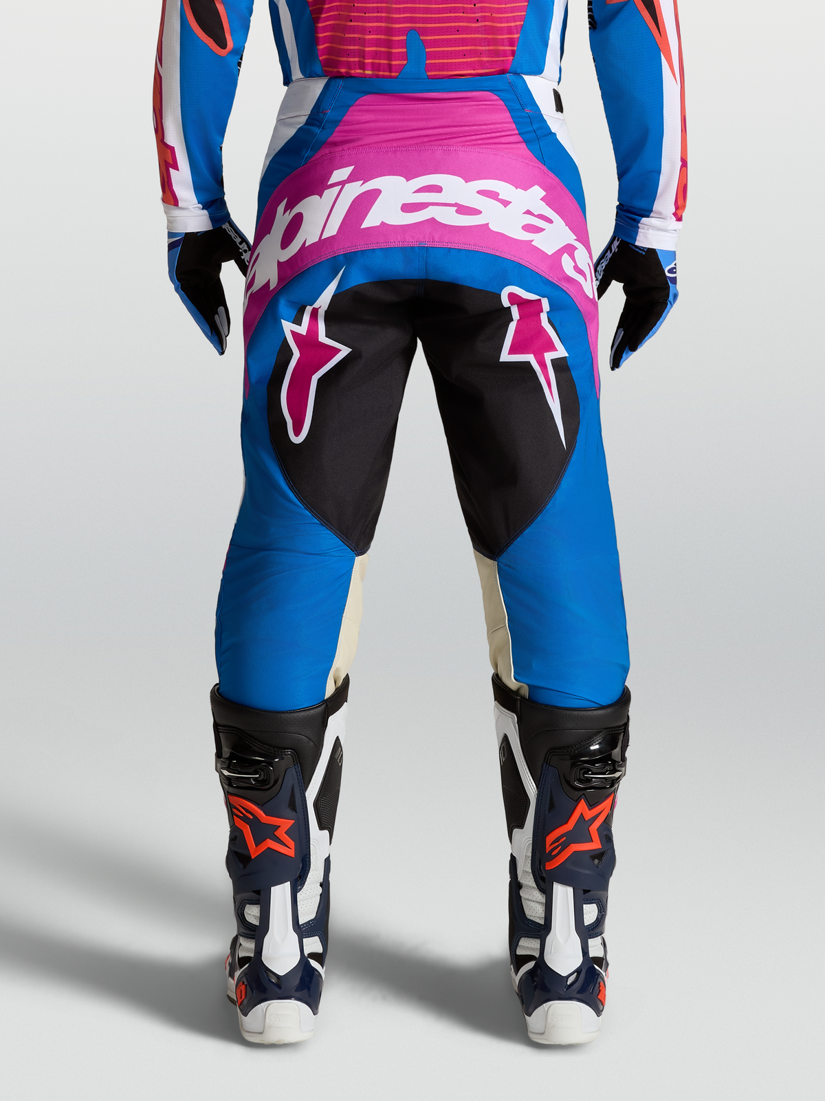 Alpinestars 2027 Techstar Maven Pants, Blue and Pink Motocross Pants on-model with star graphics and reinforced seat area.