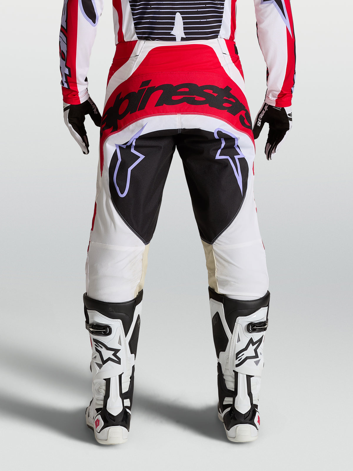 Alpinestars Techstar Maven motocross pants in red, white, and black, featuring a reinforced seat and athletic race fit.