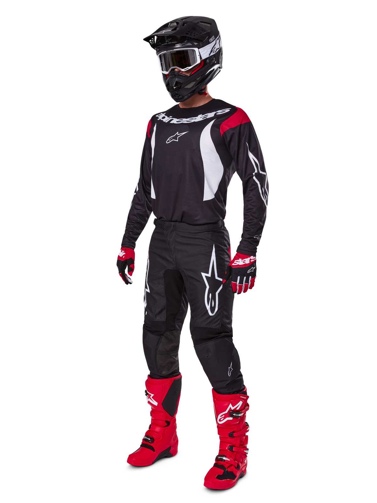 Motocross rider wearing complete Alpinestars 2025 Fluid Haul Gear Set, Black jersey with red and white accents, black pants with white logos, bright red boots, red and black gloves, black helmet with goggles, coordinated off-road performance gear