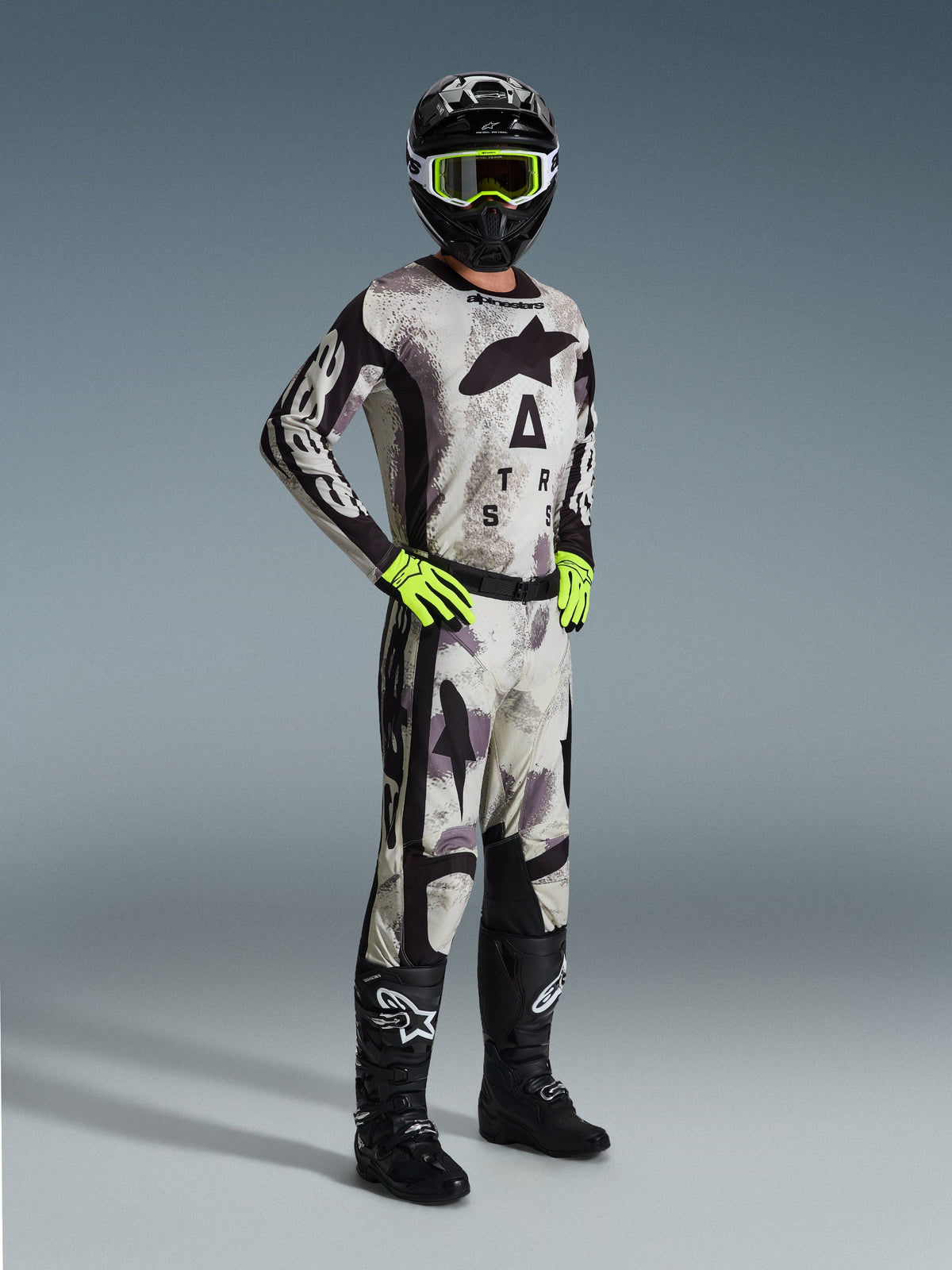 Alpinestars 2026 Racer Lahnd Gear Set, motocross-udstyr, Sand Camo, matchende camo-trøje med markant branding, sort hjelm med neongule briller, neongrønne handsker, sorte støvler, professionelt outfit til off-road performance