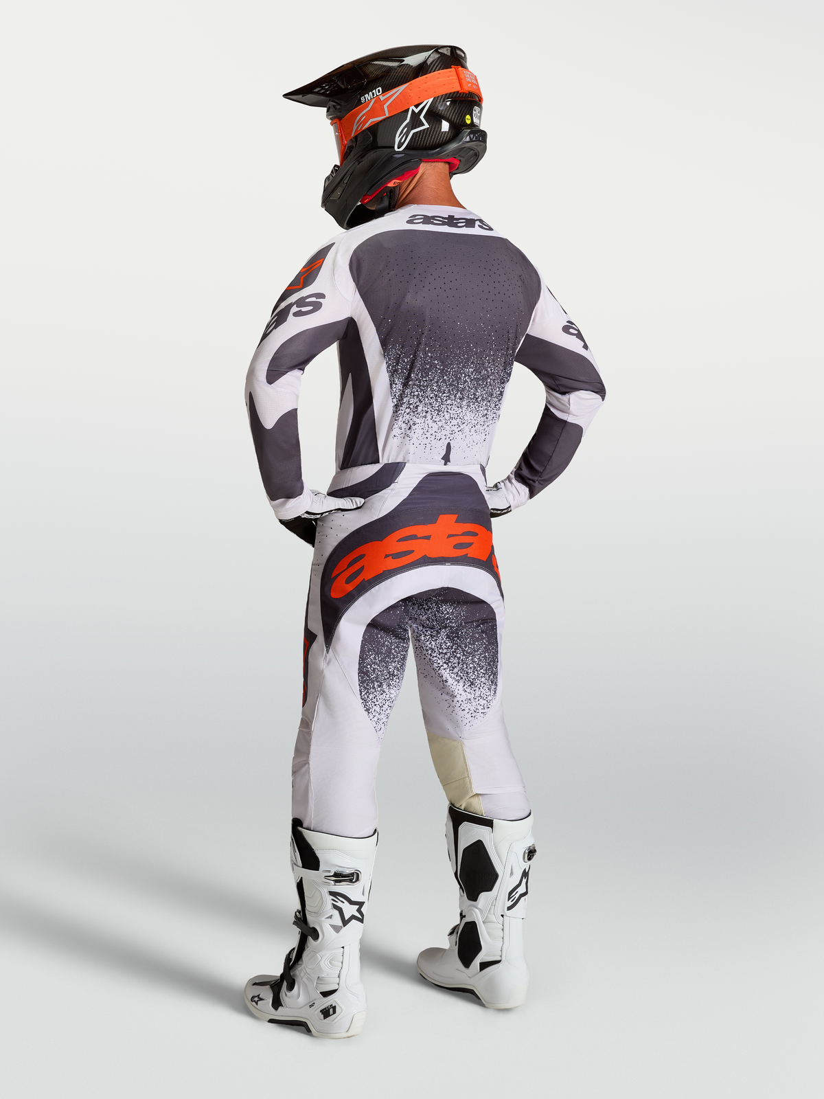 Alpinestars Techstar Swan trøje og bukser, herremotocrosstøj i grå og hvid med rød fluo, set bagfra på model.