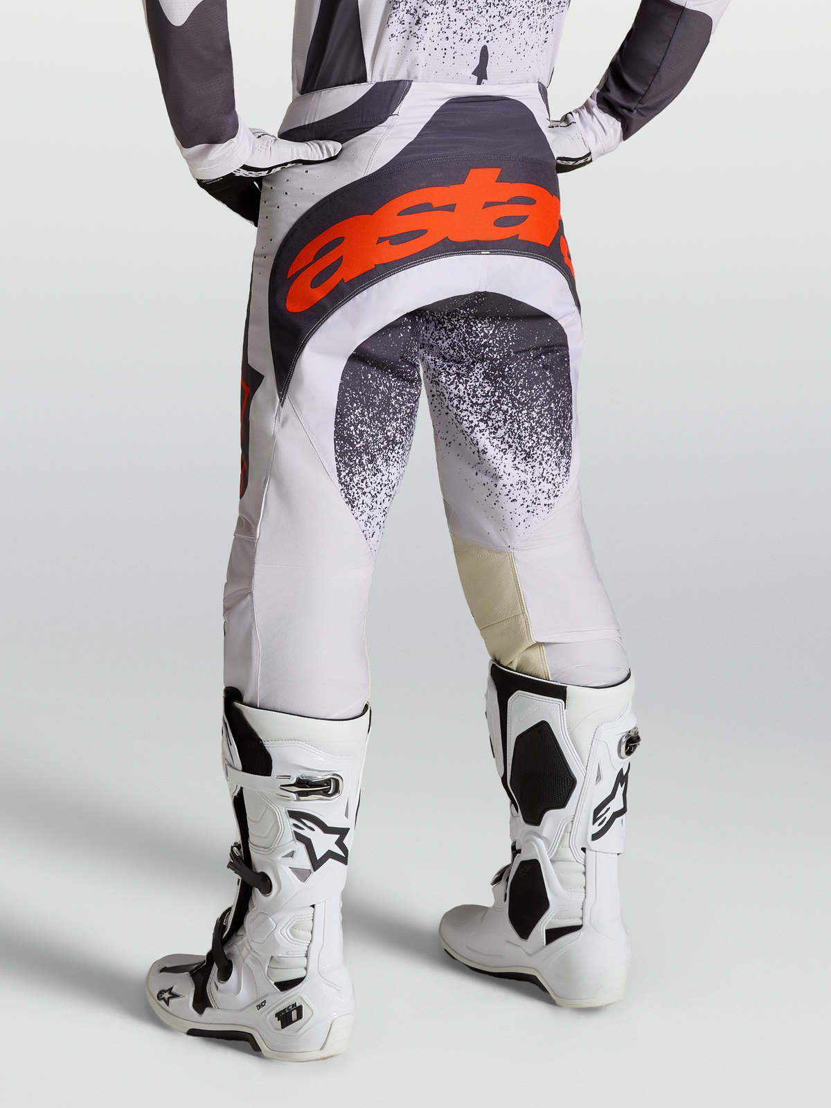 Alpinestars Techstar Swan bukser, motocross-racingbukser til mænd, lilla og grå med røde fluo-detaljer, båret med Tech 10 støvler.