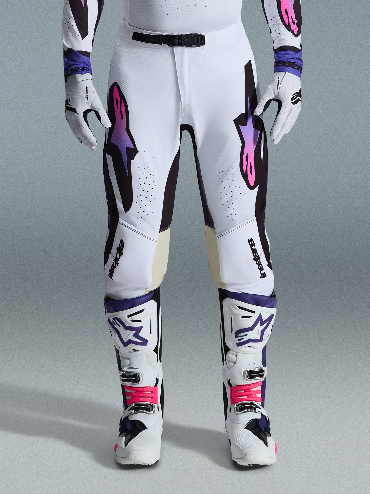 Alpinestars 2026 Supertech AFD Vista bukser, motocross-bukser, hvid, lilla og sort, båret med matchende hvide støvler og handsker, med pink-til-lilla gradient Astars-logoer på lårene, professionelt racing-design til off-road-performance.