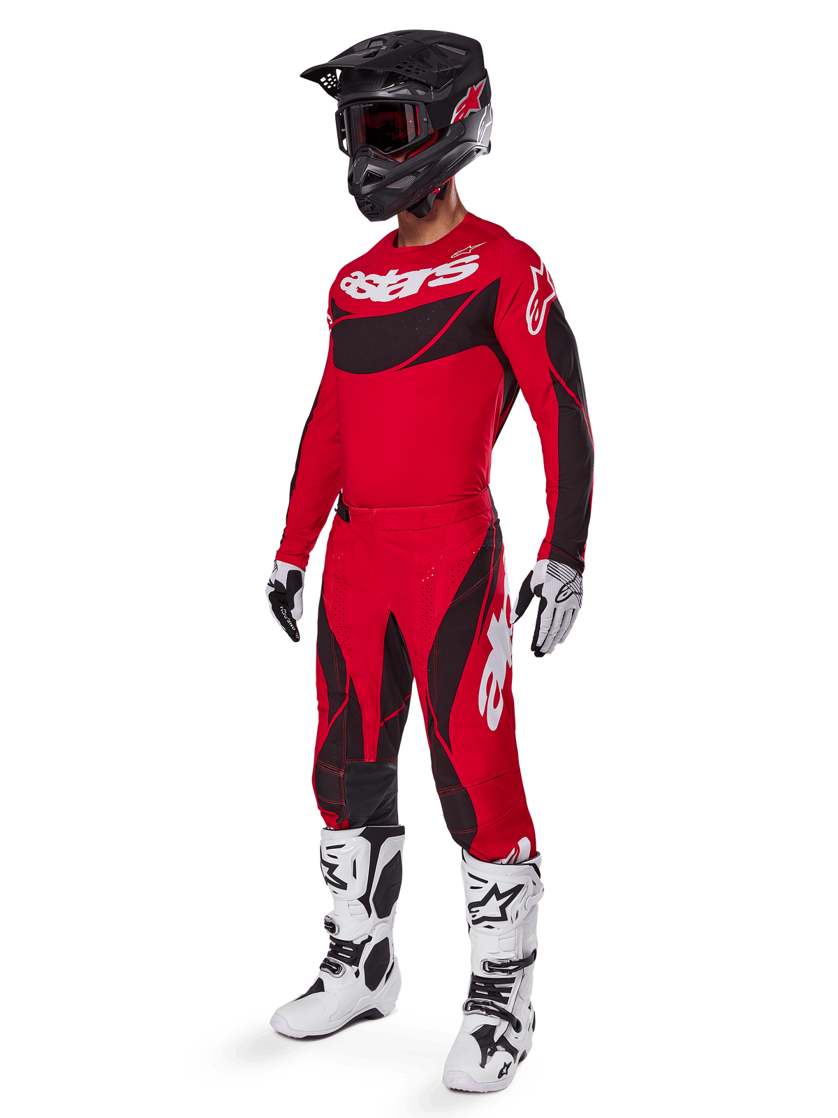 Motocross-kører iført komplet racerudstyr med Alpinestars 2025 Techstar Dreem bukser i klar rød og sort, matchende rød og sort trøje med hvidt logo, sort hjelm og hvide og sorte støvler, koordineret outfit til off-road racing