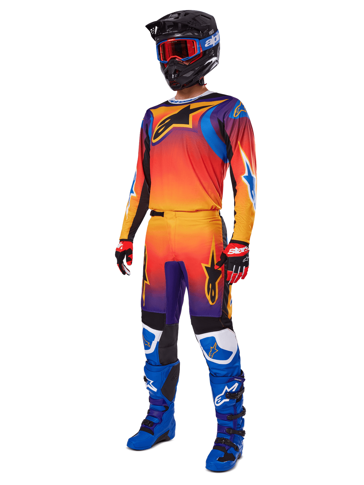 Motocross-rytter iført komplet racerudstyr, Alpinestars 2025 Fluid Wurx-bukser og matchende trøje i en flerfarvet orange, rød og lilla graduering, sort hjelm med røde briller, blå og sorte støvler, røde og sorte handsker, koordineret outfit til off-road kørsel