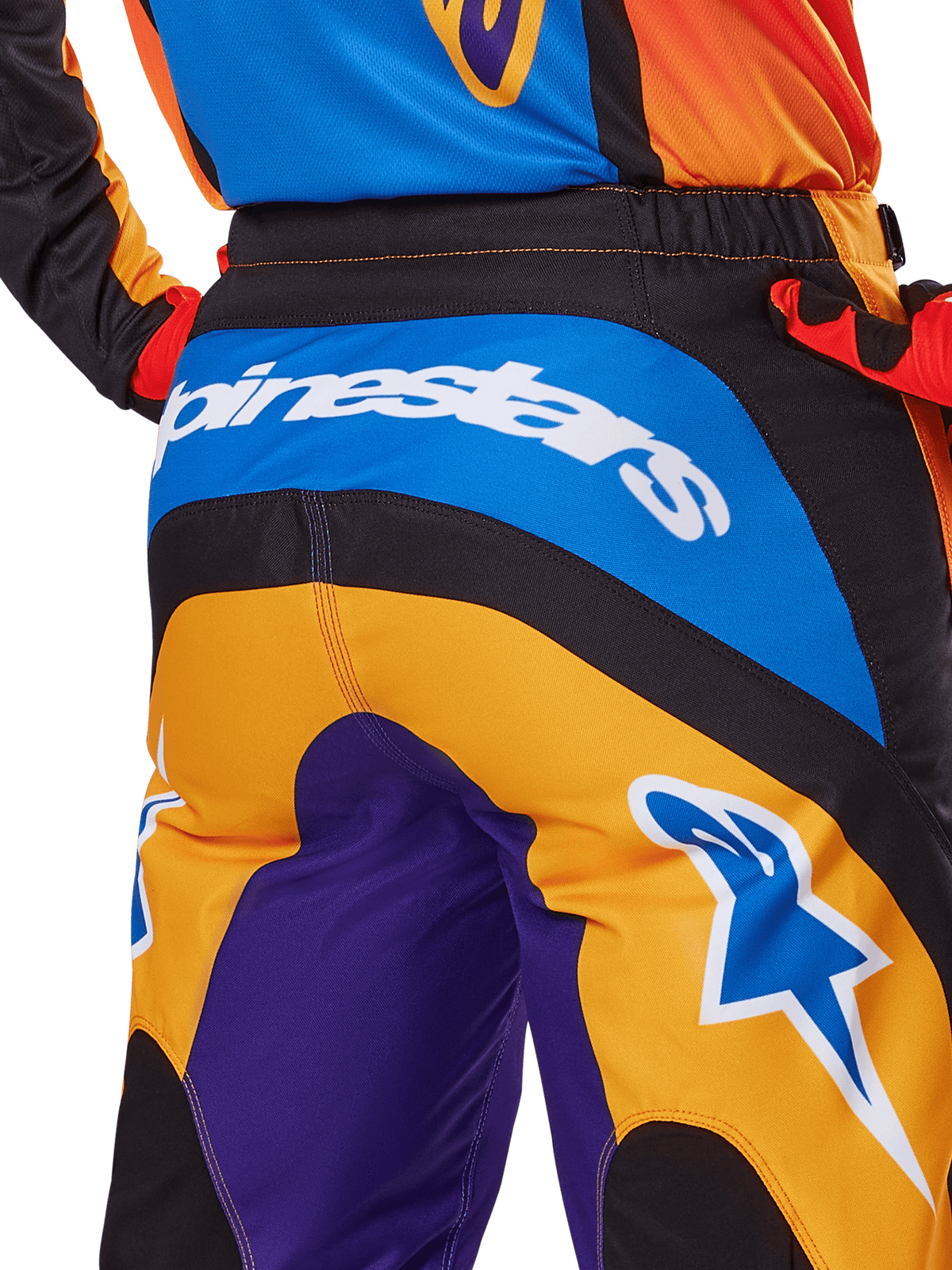 Alpinestars 2025 Fluid Wurx bukser, motocross-bukser, set bagfra i orange, blå og lilla, hvidt Alpinestars-logo over sædet, blåt Astar-logo på benet, teknisk konstruktion til terrænkørsel