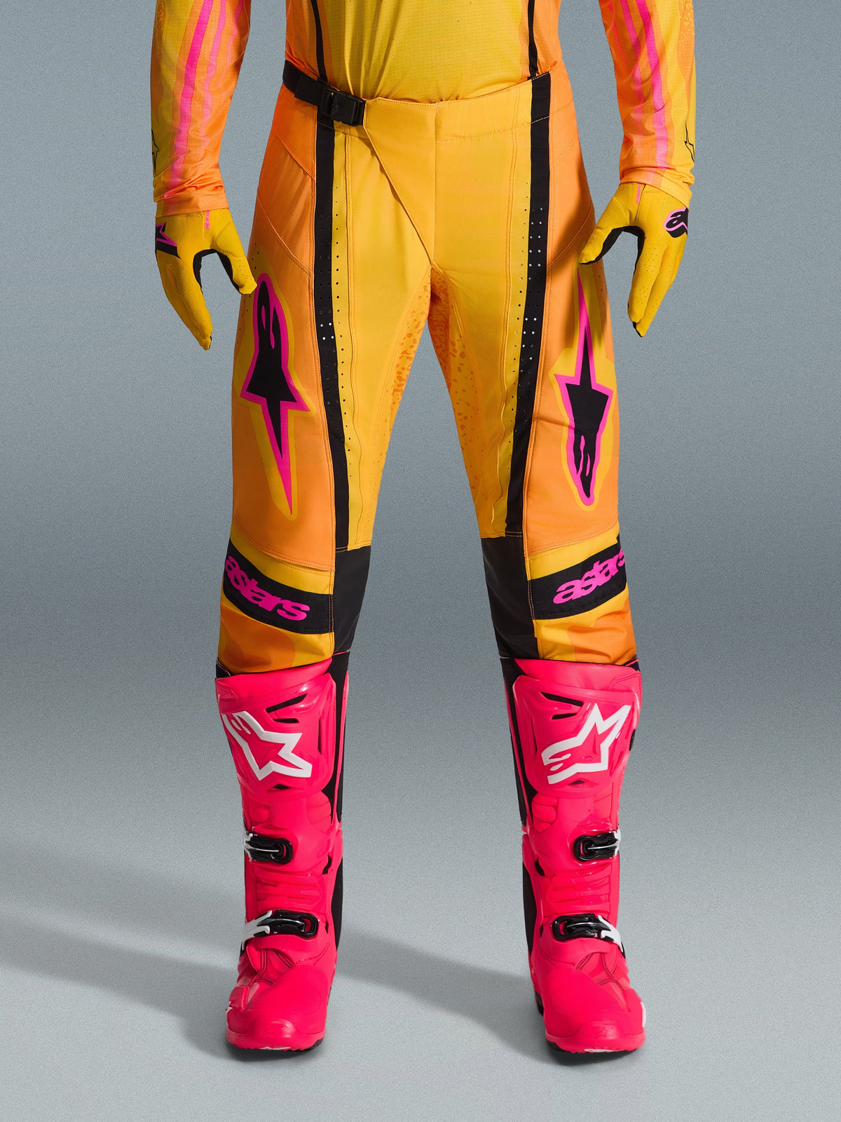 Alpinestars 2026 Techstar Nomur bukser, motocross-bukser, orange, gul og pink, båret med matchende gule handsker og stærke pink racerstøvler, med sorte paneler og markant pink Alpinestars-branding, teknisk off-road racerudstyr