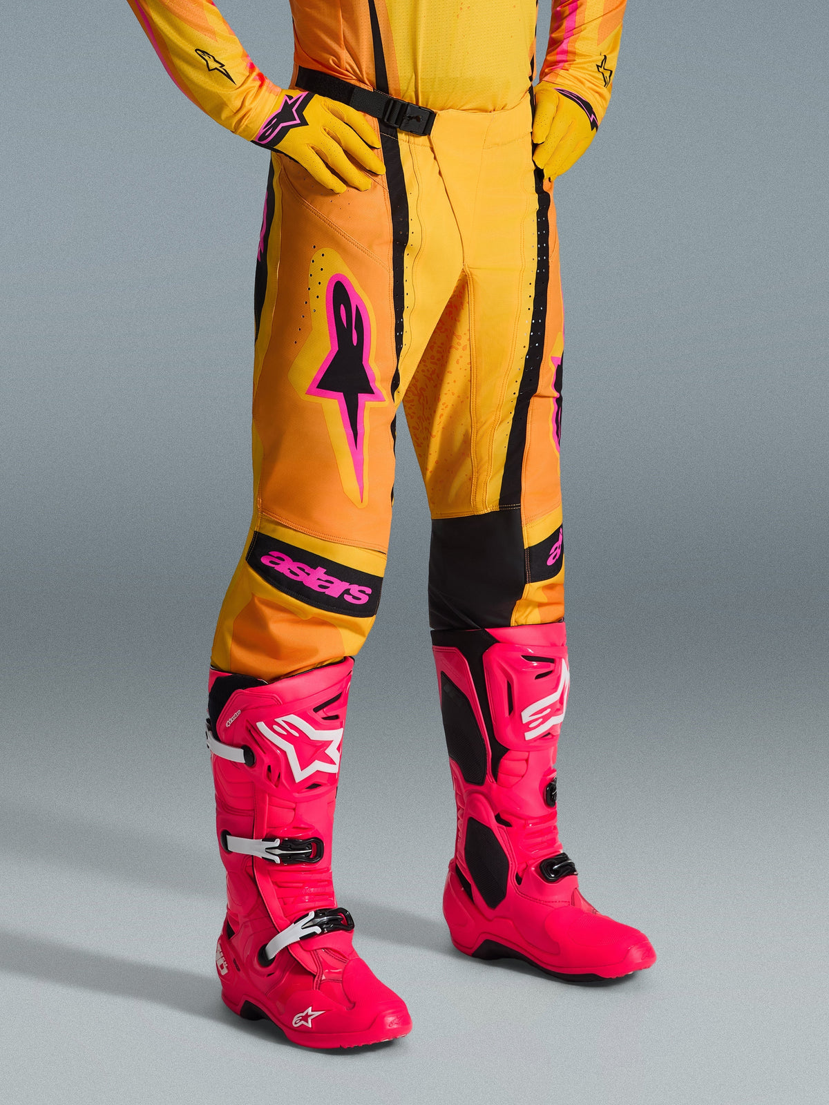 Alpinestars 2026 Techstar Nomur bukser, motocross-bukser, orange, gul og pink, båret med matchende gul trøje og handsker samt skarpe pink støvler, atletisk race-pasform med pink branding og sort magnetisk spænde, iøjnefaldende gear til off-road konkurrence