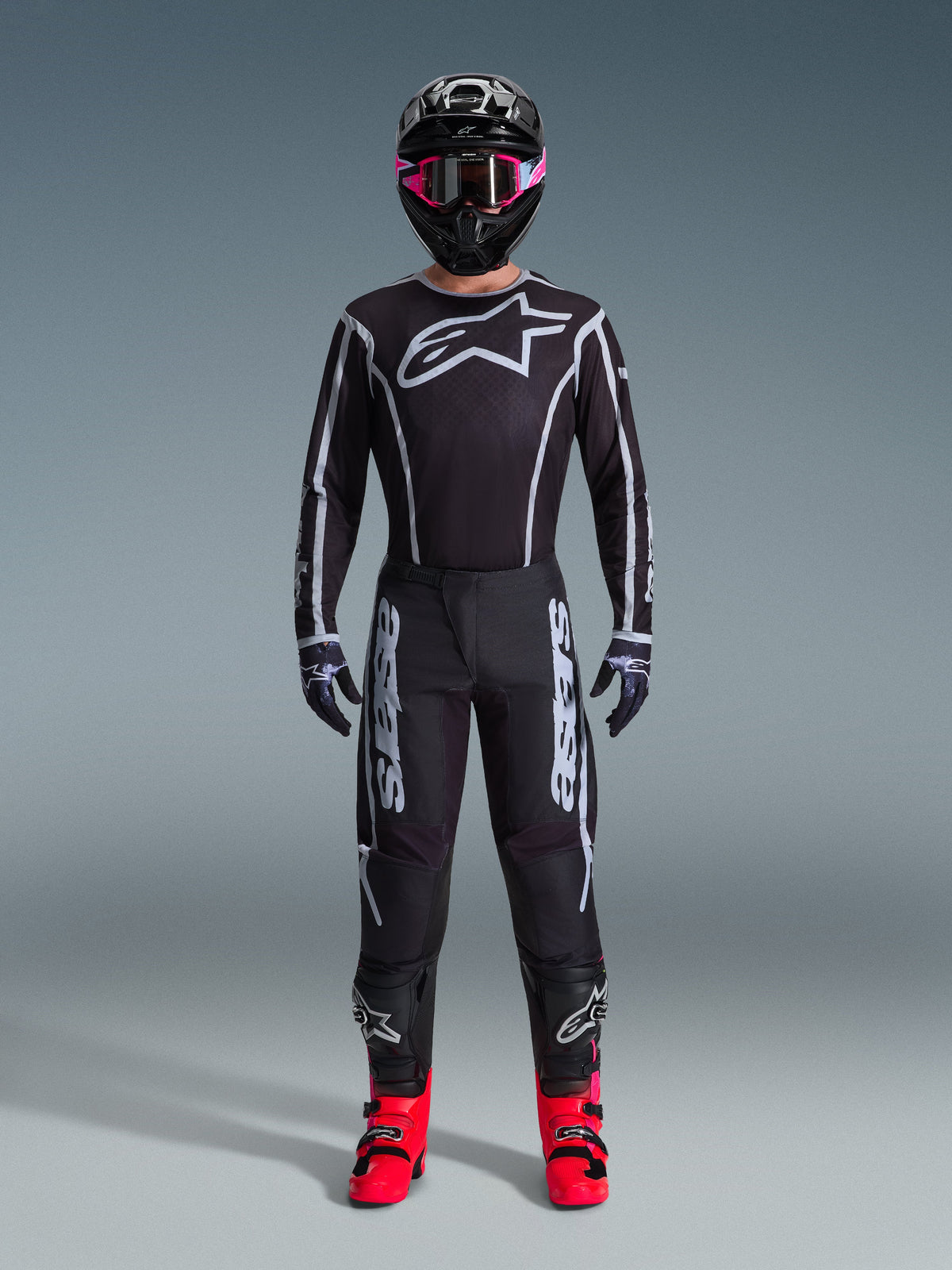 Alpinestars 2026 Fluid Apex-udstyrssæt, motocross-outfit, sort med grå detaljer, jersey med stort hvidt Astars-logo, matchende bukser med tydelig branding, sort hjelm med pink goggles og stærkt røde støvler, komplet off-road racerudstyr