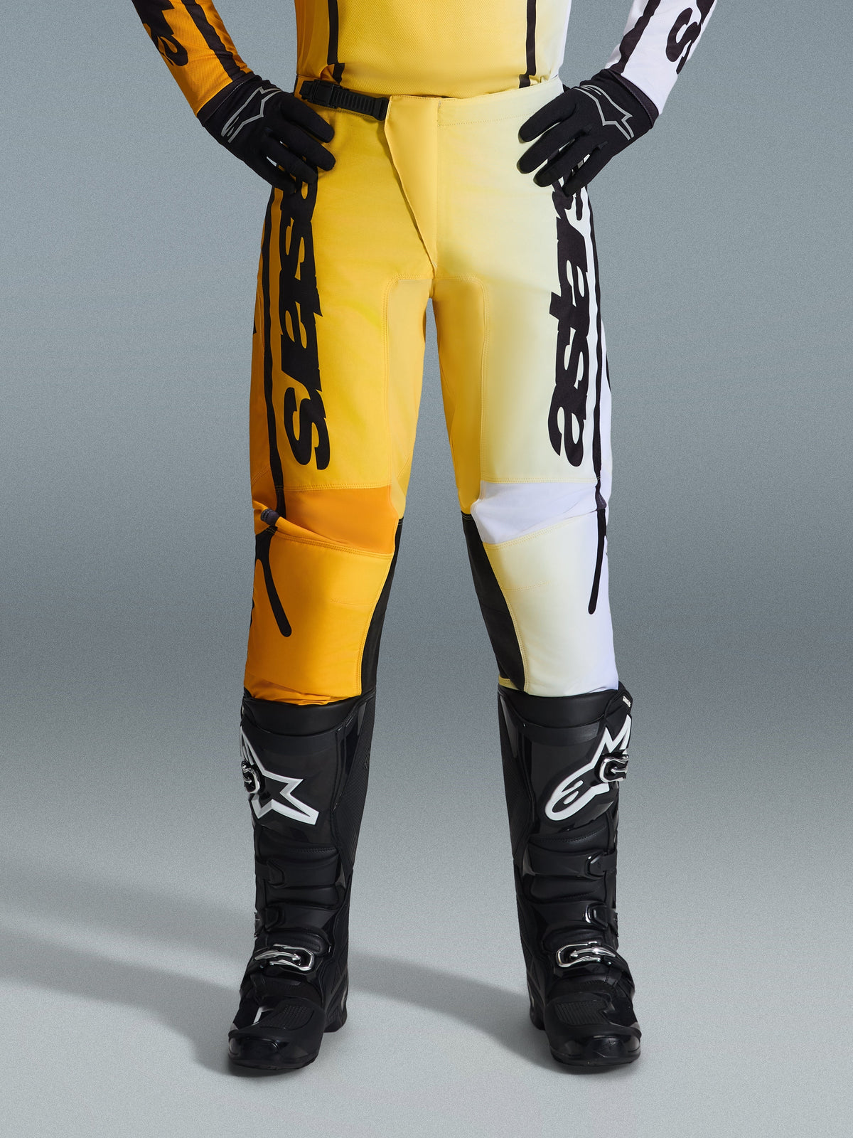 Alpinestars 2026 Fluid Apex bukser, motocross-bukser, gul og sort, split-farve design med gule og hvide paneler, markant lodret 'astars' branding, bæres med sorte motocross-støvler og handsker, performance-udstyr til terrænkørsel